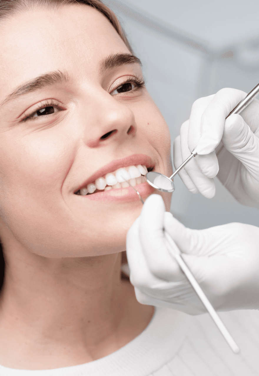 A close-up of a woman smiling during a dental check-up, with a dental professional using dental tools to examine her teeth.