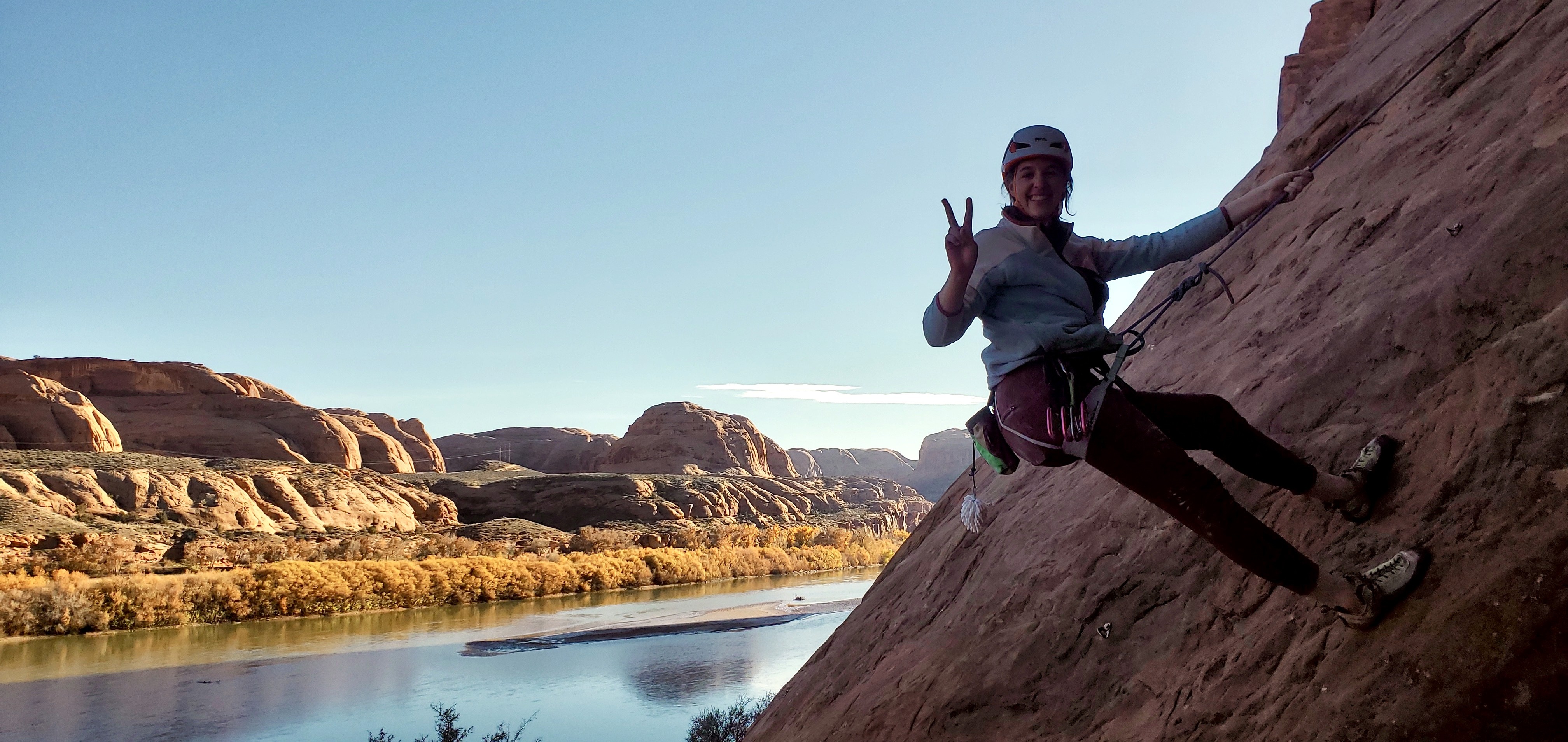 Young woman standing on cliff face attached to a rope