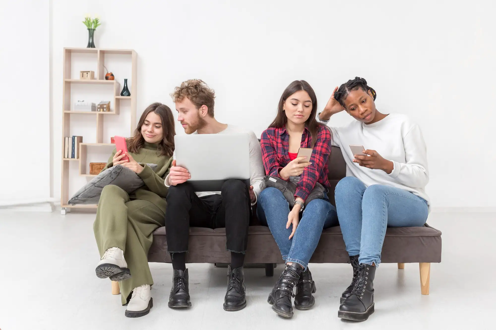 Diverse group multitasking across devices on couch, demonstrating the 32-hour digital day and fragmented media consumption habits