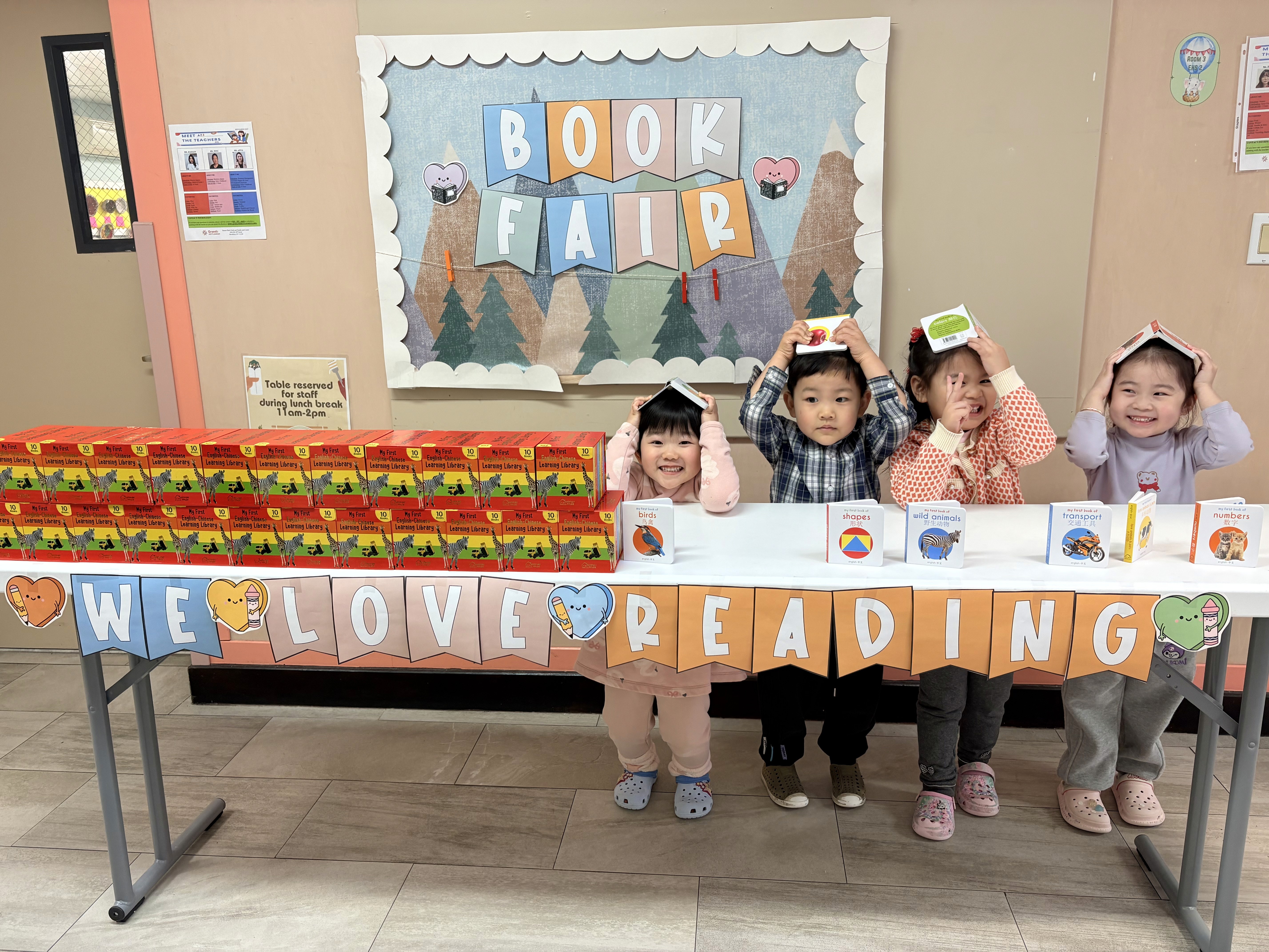 Pre-k students put books on their head in a silly manner at the Sunset Park book fair.