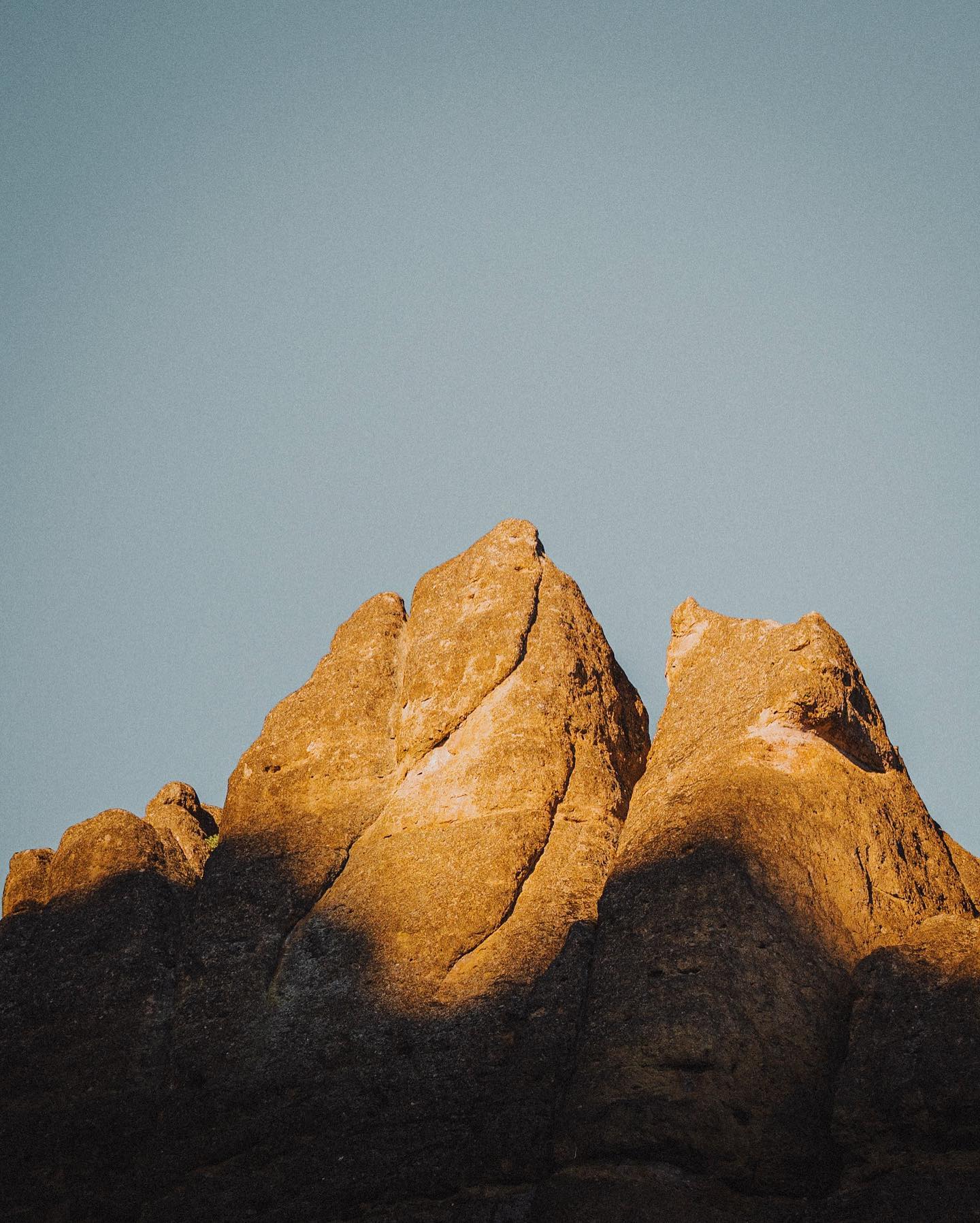 A rocky spire in Pinnacles National Park under a bright blue sky.