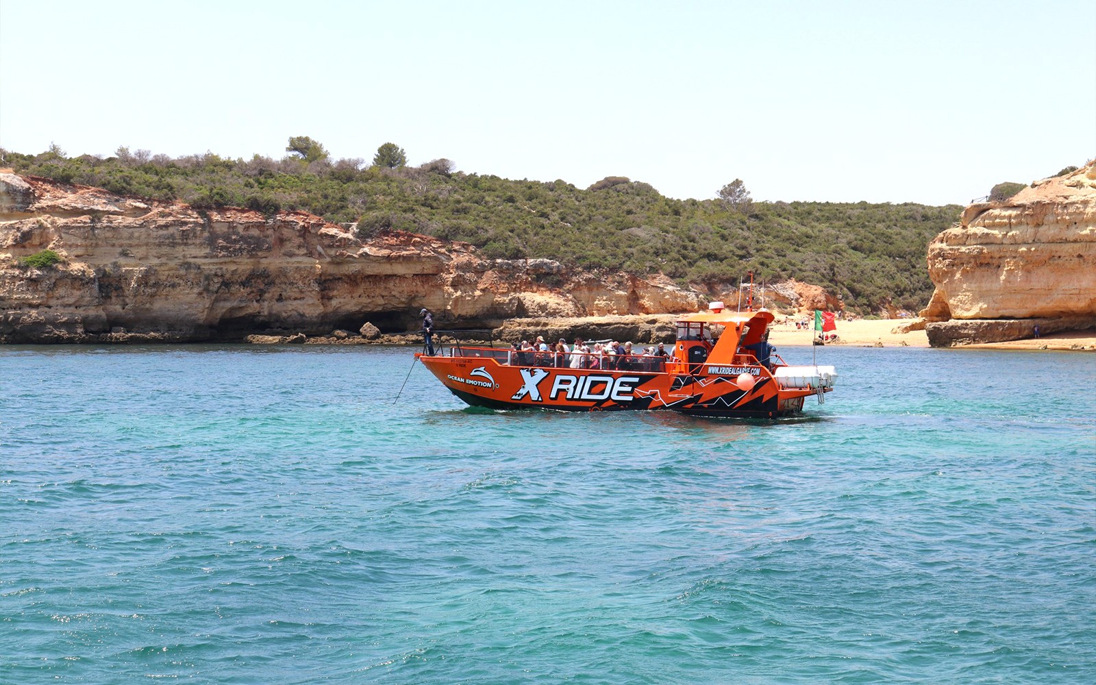 Boat tour near Benagil Caves with passengers, Albufeira coastline in background.