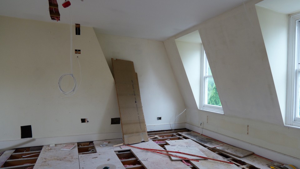 Loft room refurbishment during HMO conversion with floorboards lifted and wiring underway