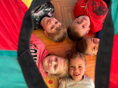 Skupina dětí ležící na zemi v kruhu hlavami k sobě