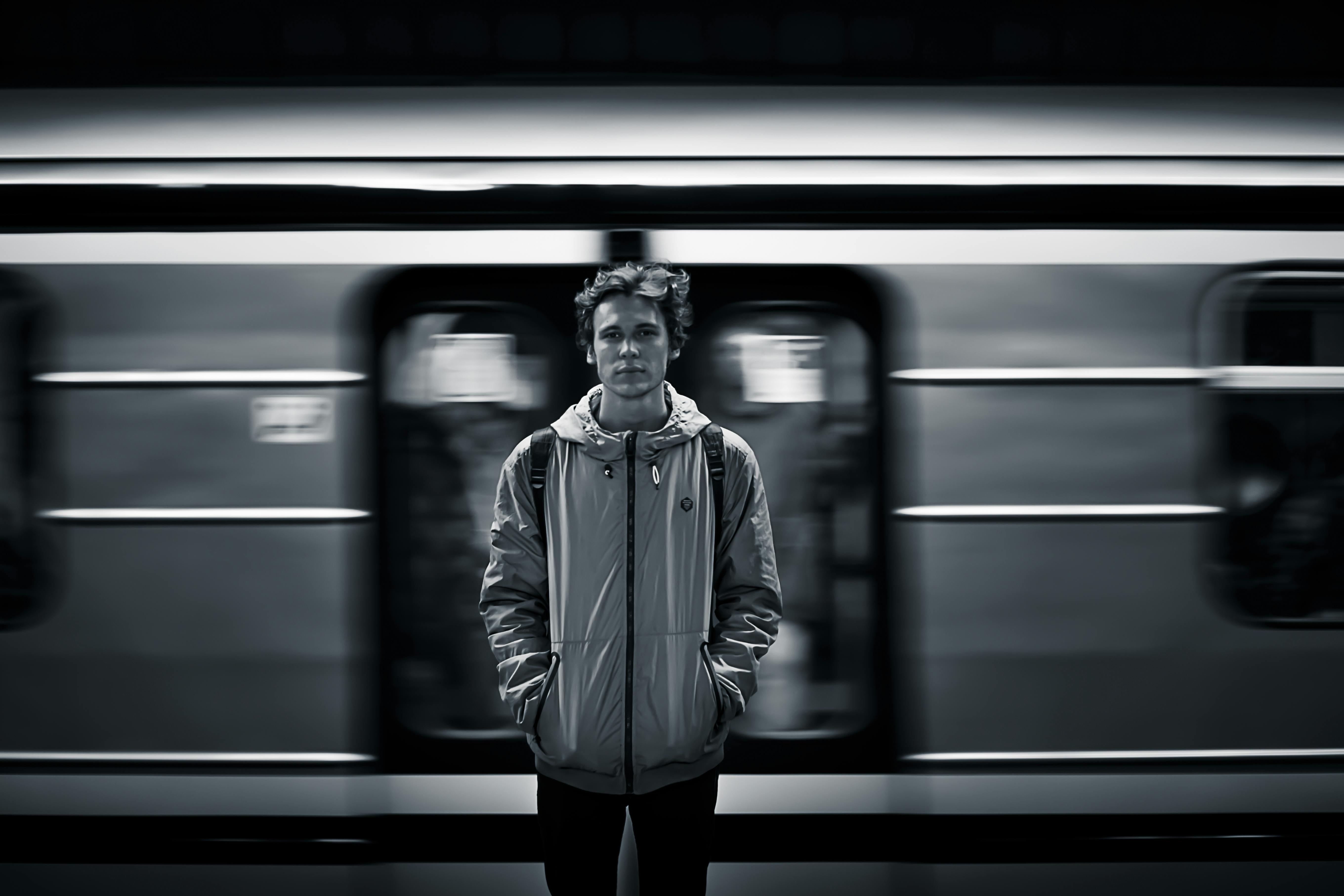 Man Wearing Windbreaker Jacket Standing on Train Station Grayscale Photography