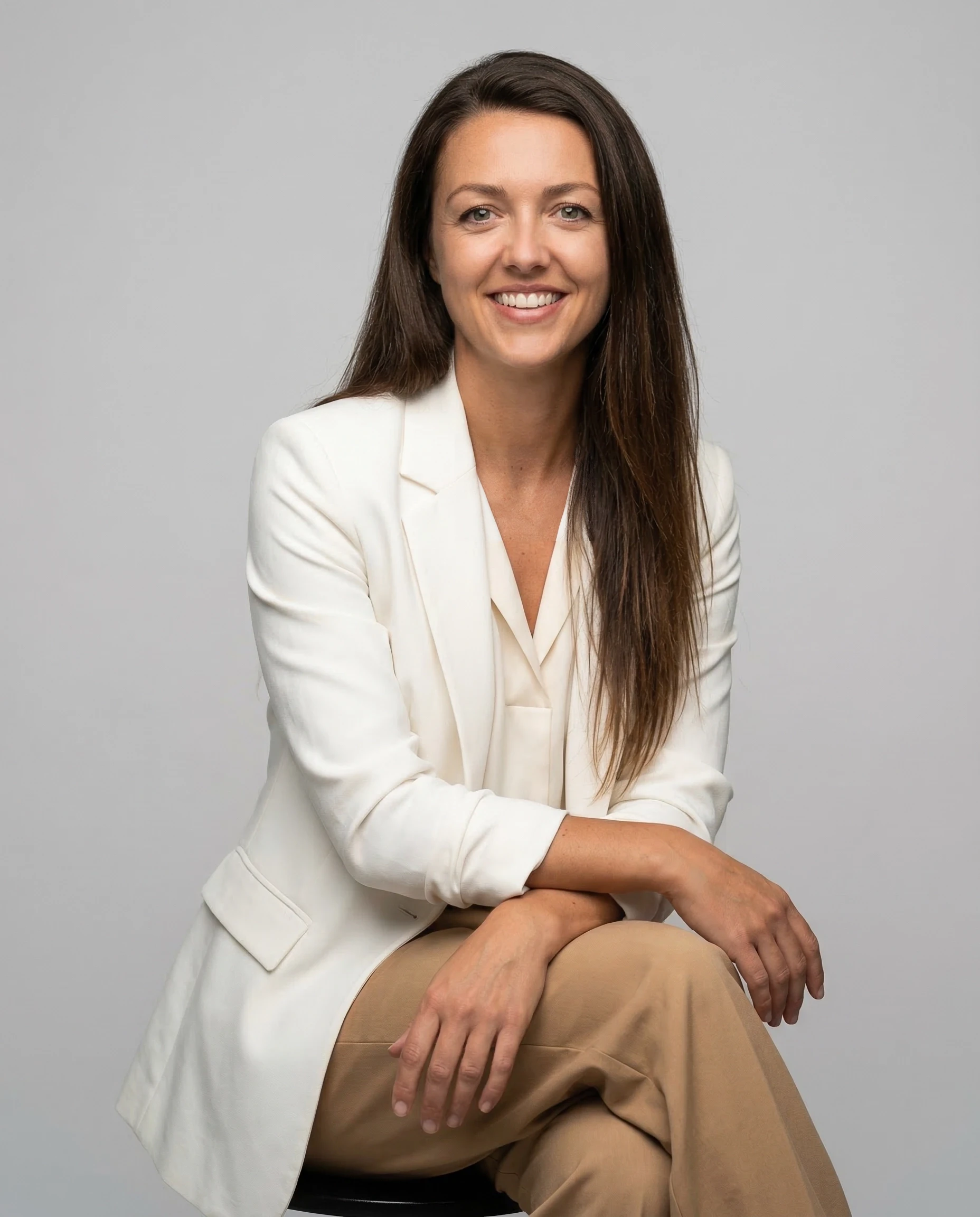 A woman lying down on a soft surface with her eyes closed, bathed in warm sunlight filtering through leaves. Her face has a natural glow, reflecting relaxation and tranquility in a serene spa-like setting.