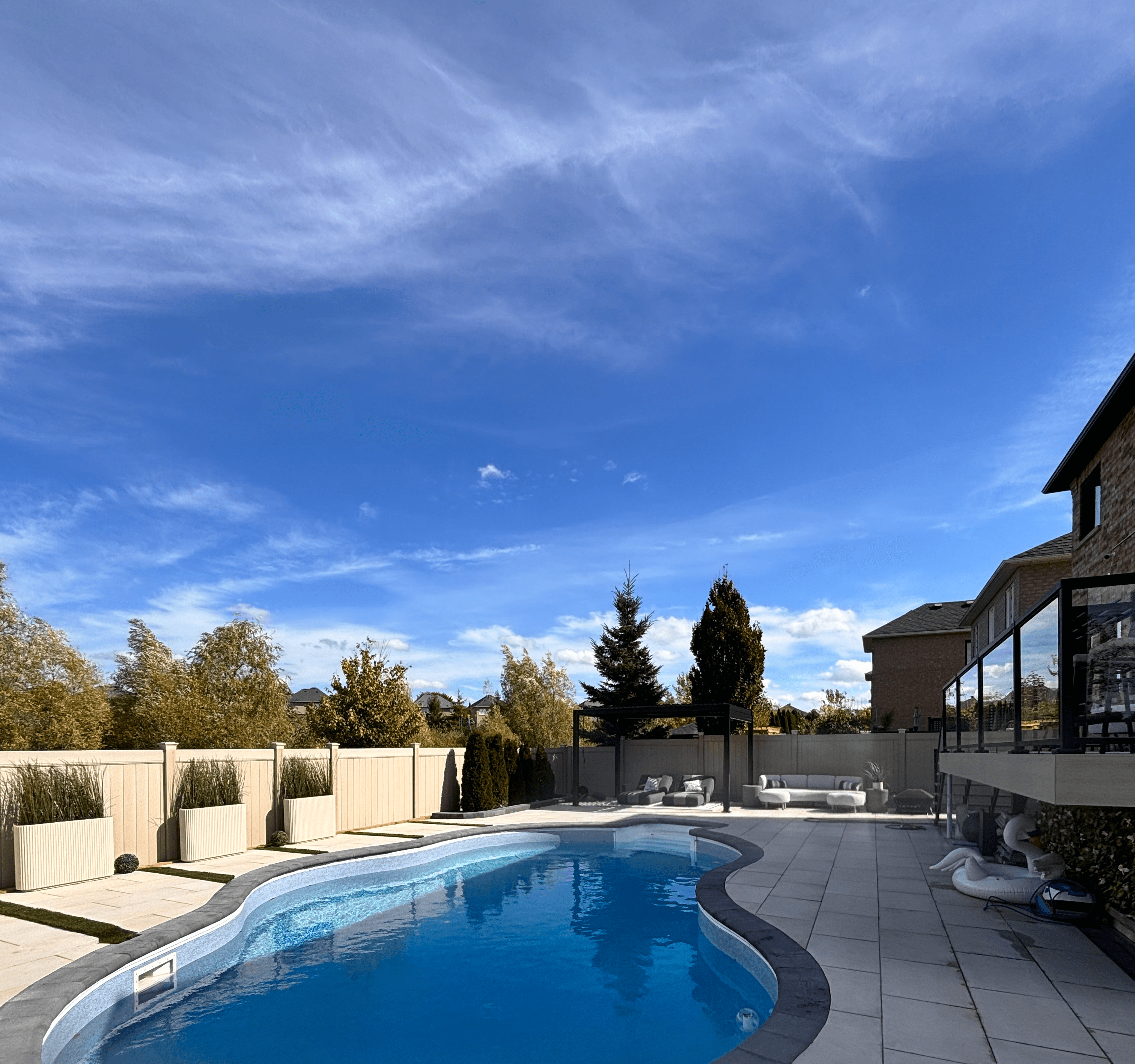Backyard scene with a patio area, trees, and a clear blue sky, creating a serene outdoor atmosphere.