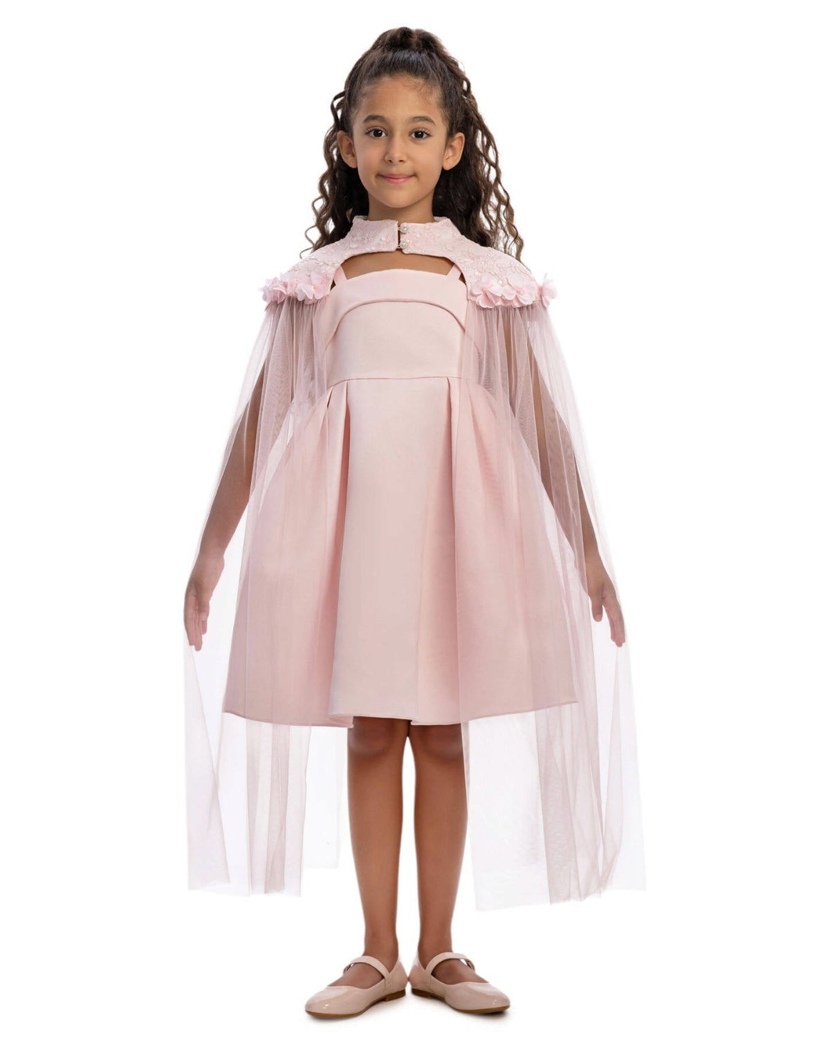Young girl wearing a pink dress with a cape on a white background