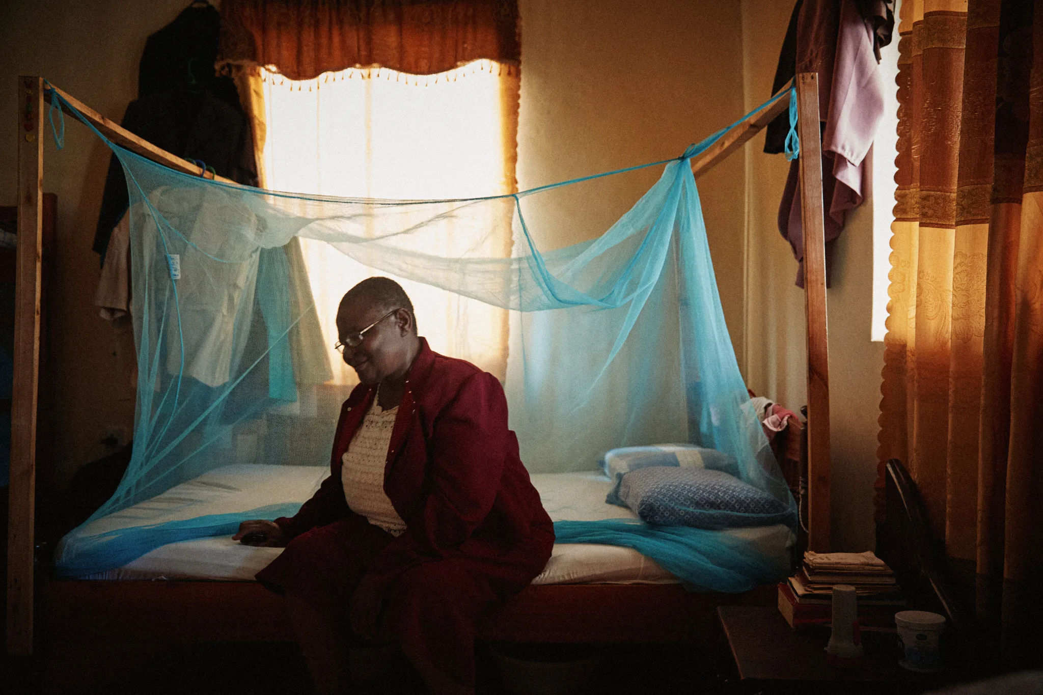 woman sitting beneath blue mosquito net — portrait photography by Tom Kubik