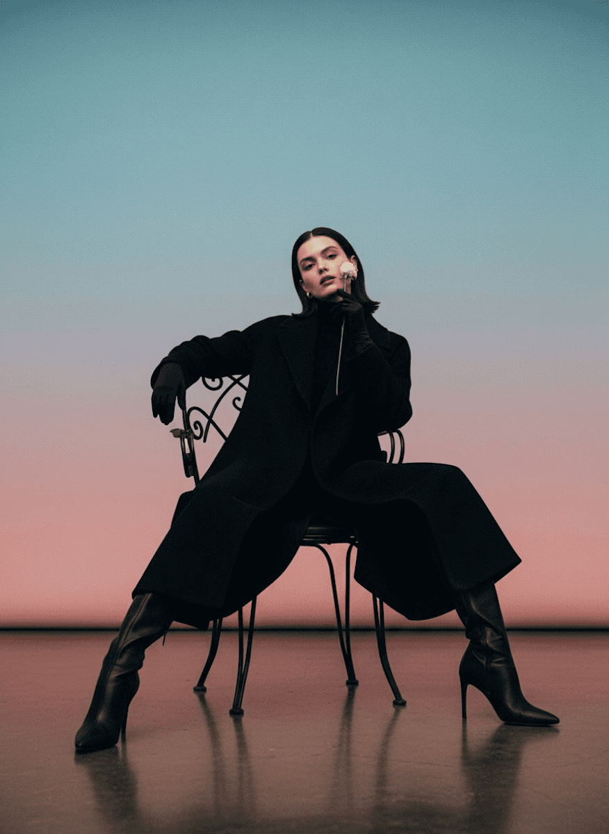 A woman posing on a chair with rose in her hand