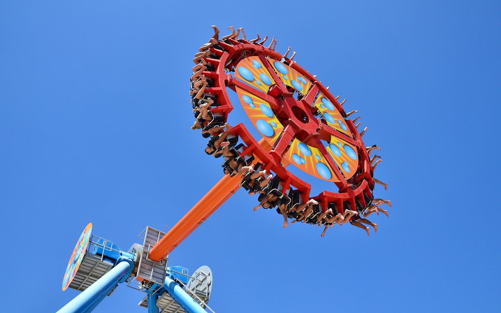 Visitors on a spinning ride at Aquashow Park against a clear blue sky.