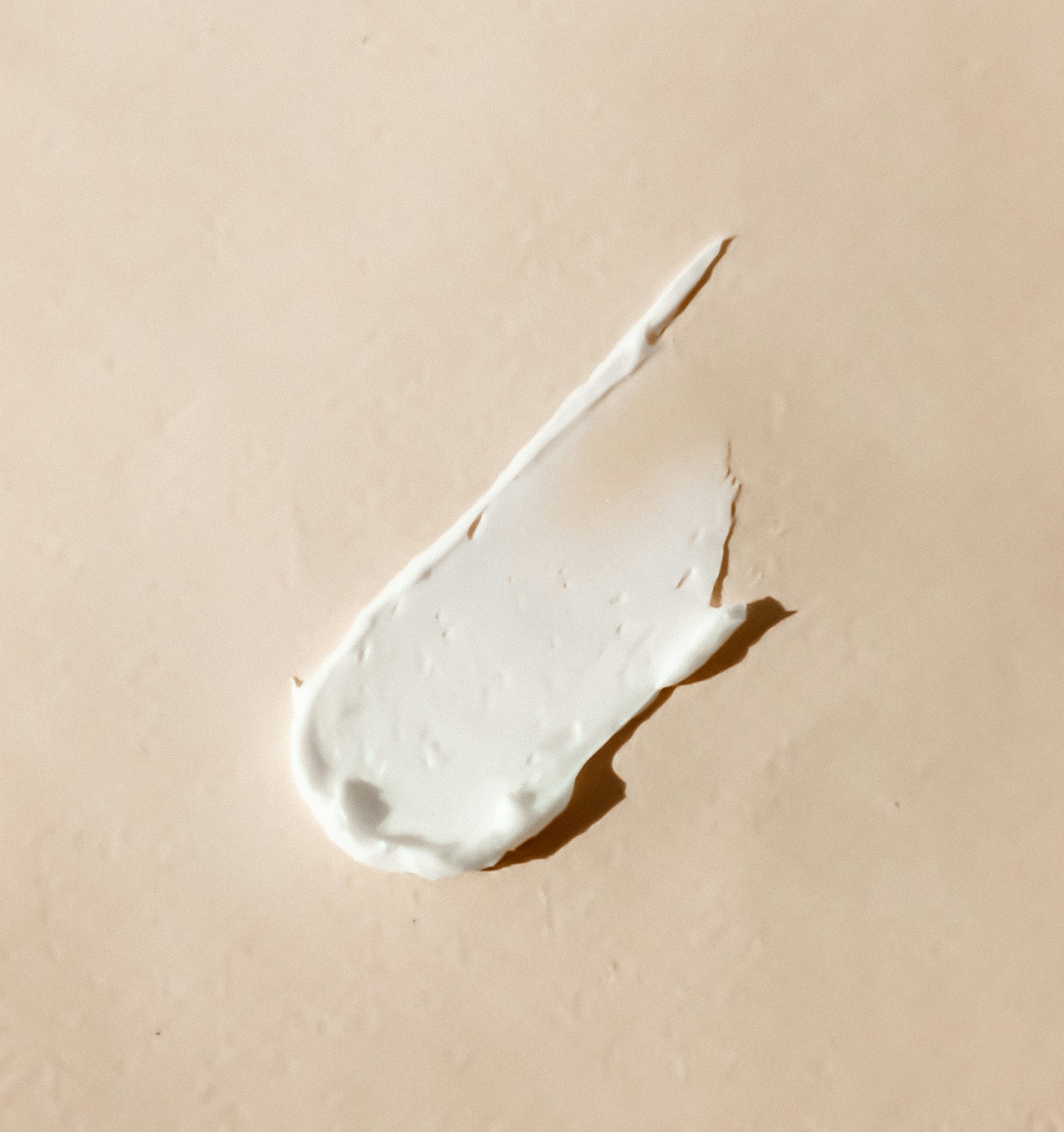 A clear serum dropper with a viscous transparent fluid against a pale background