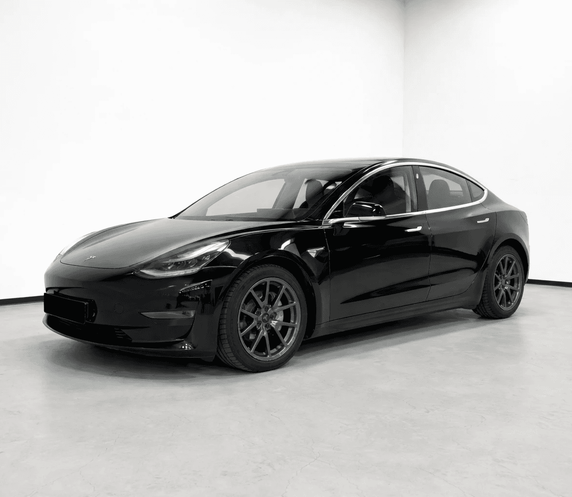 Tesla Model 3 noire en studio photo, berline électrique vue de face dans un décor minimaliste
