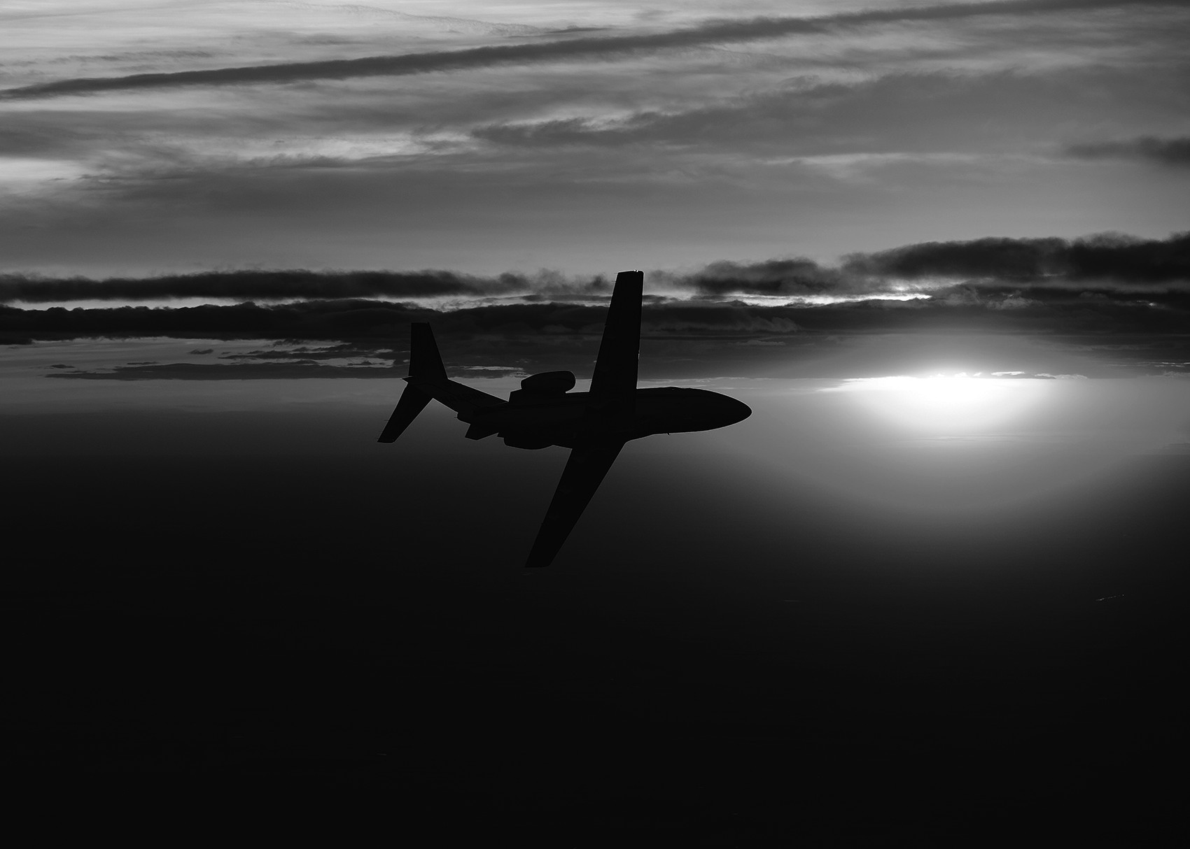 A Cessna Citation jet turning into the far off horizon as the sun is setting