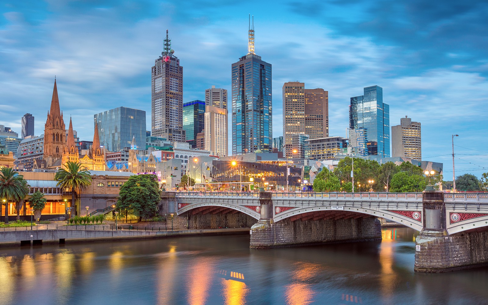 Melbourne city skyline with Yarra River and bridge at dusk.
