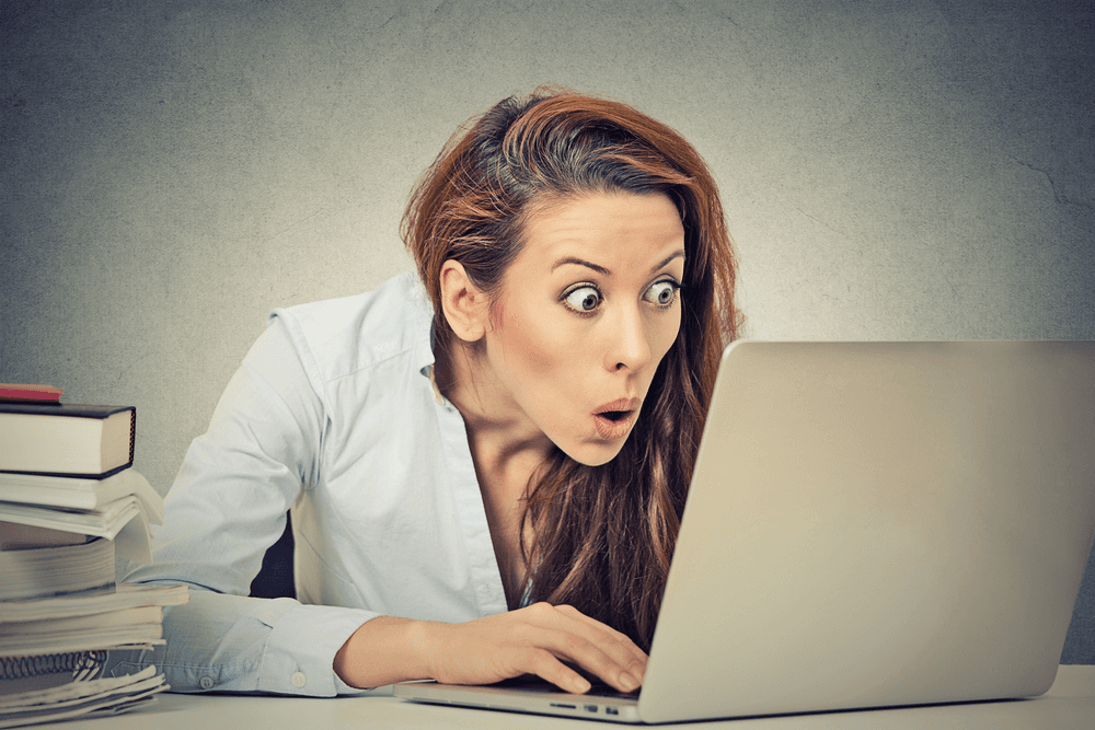 A person with long hair working on a laptop at desk.
