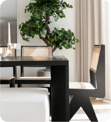 Sophisticated dining area with a black table, modern cane chairs, and a green potted plant, exemplifying Click Media Group’s eye for composition and detail in property photography.