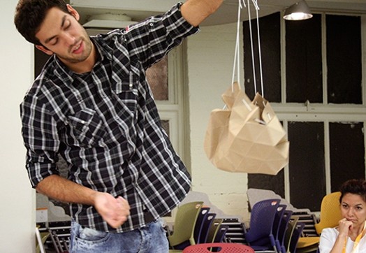 A photo of a man wearing a shirt and holding what looks like a paper bag.