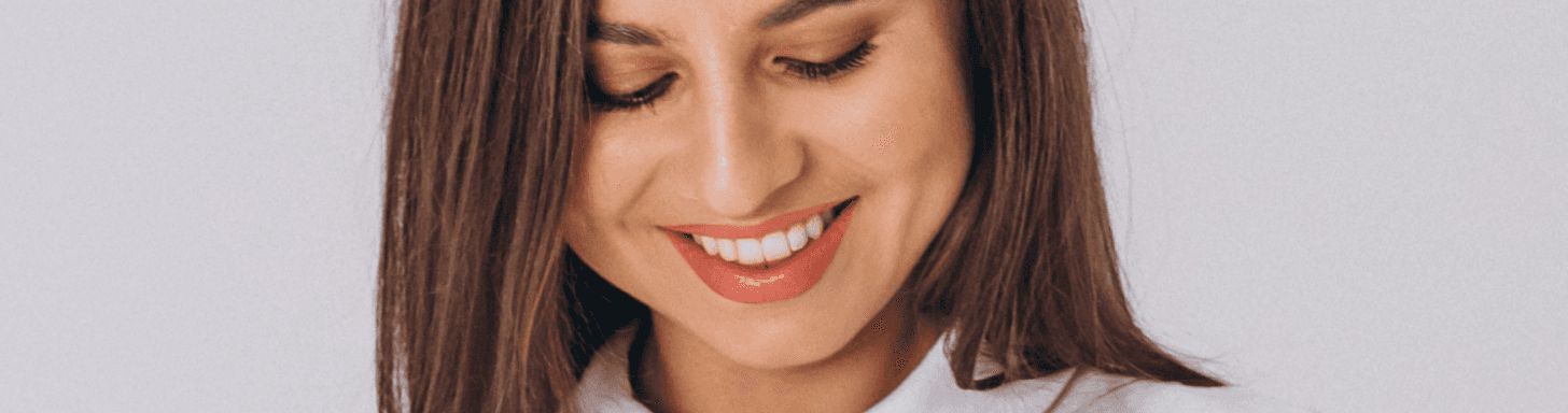 A close-up of a smiling woman looking down, showcasing her healthy teeth.