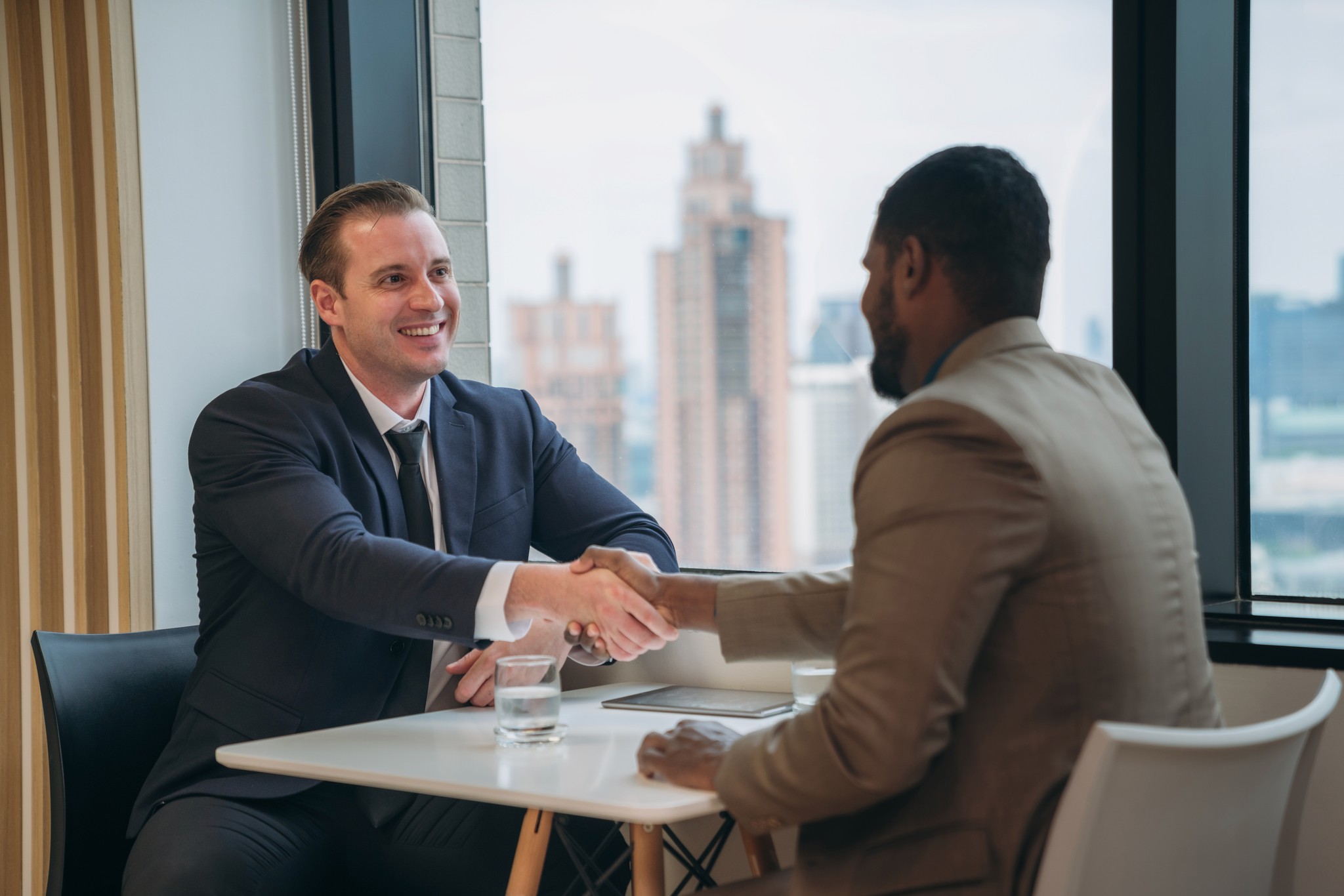 A winding road cuts through rocky terrain, surrounded by patches of green grass and illuminated by sunlight.