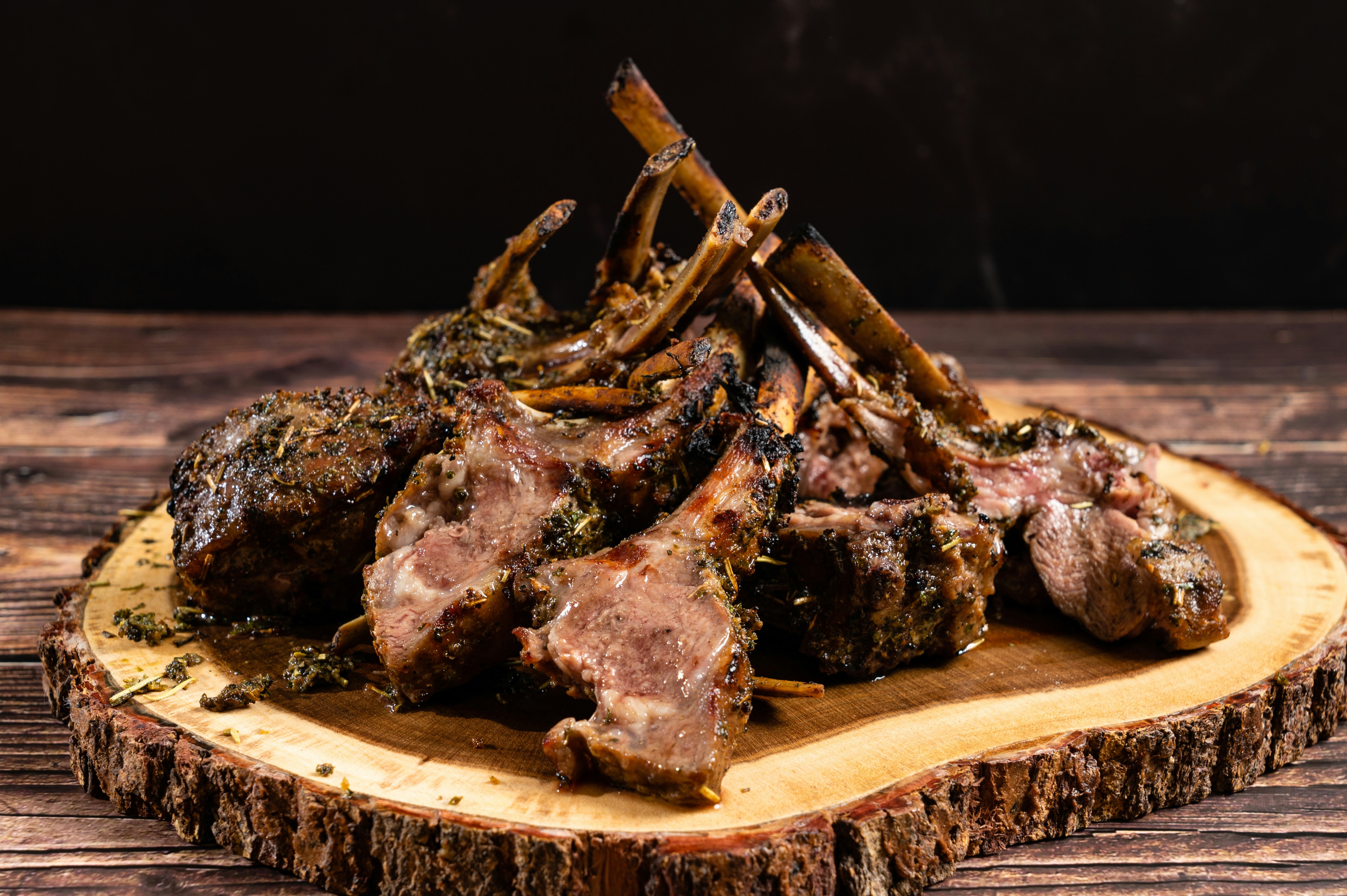 Roasted lamb chops plated on a wooden serving board.