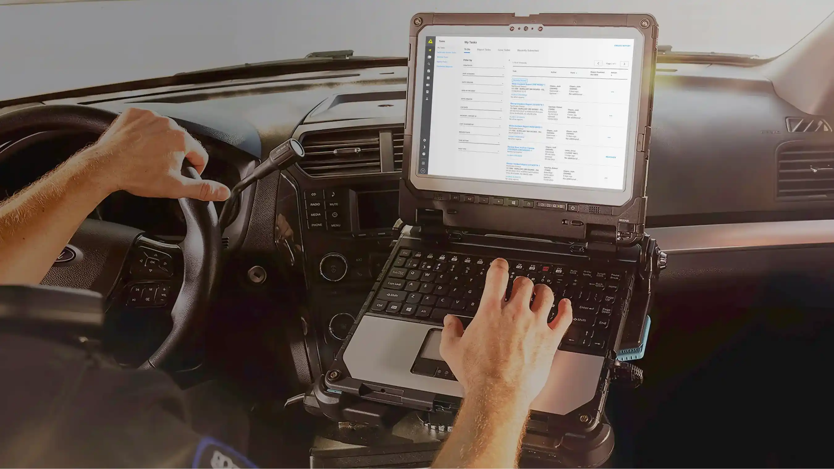 A police officer in a patrol car using a laptop to view the Axon Records task list, showing a queue of pending incident reports.