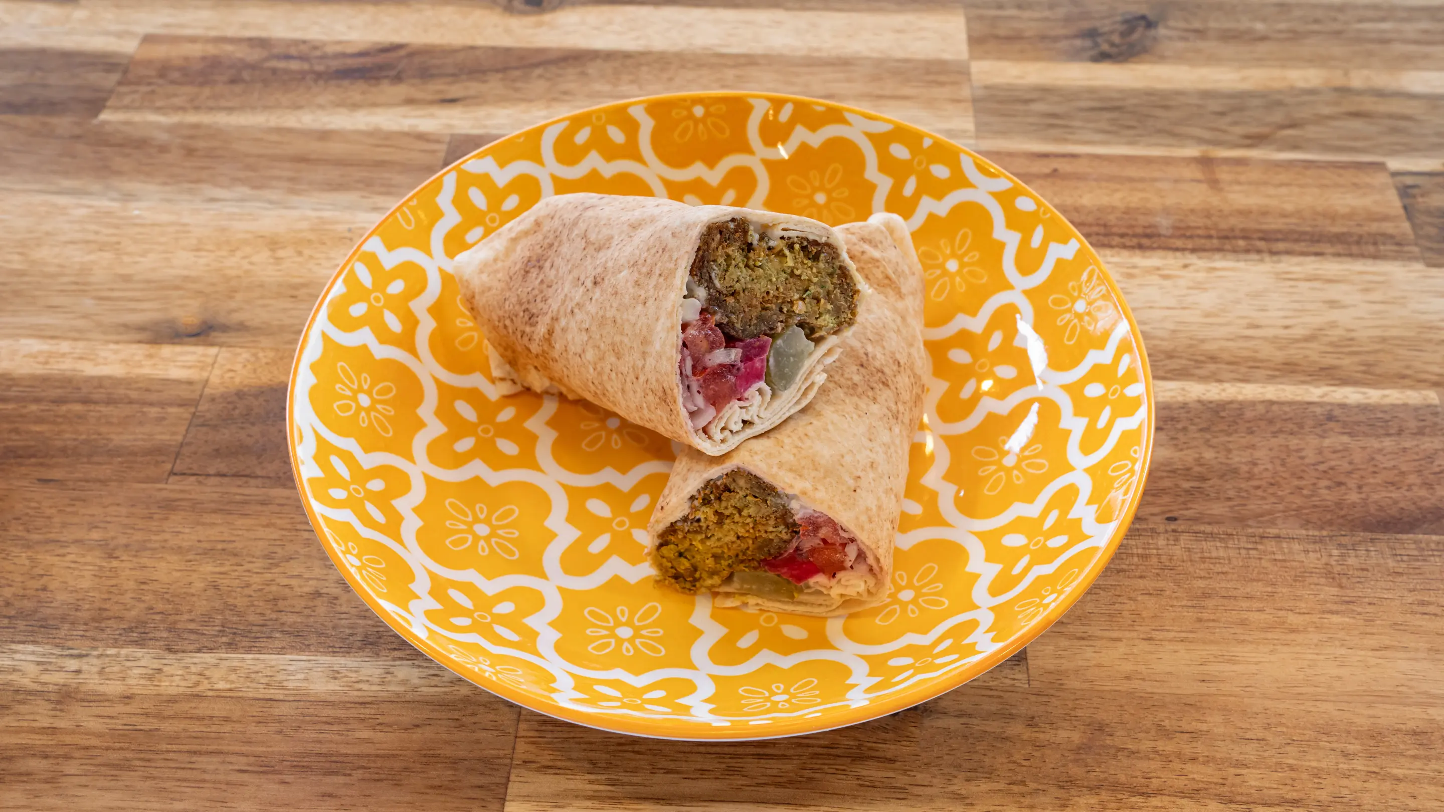 Sandwich libanais farci de falafels posé sur une assiette jaune