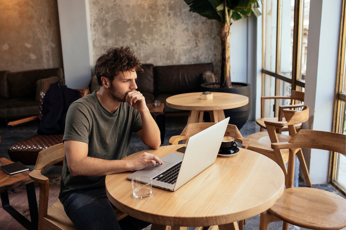 A person working at a table with a laptop in an cozy cafe.