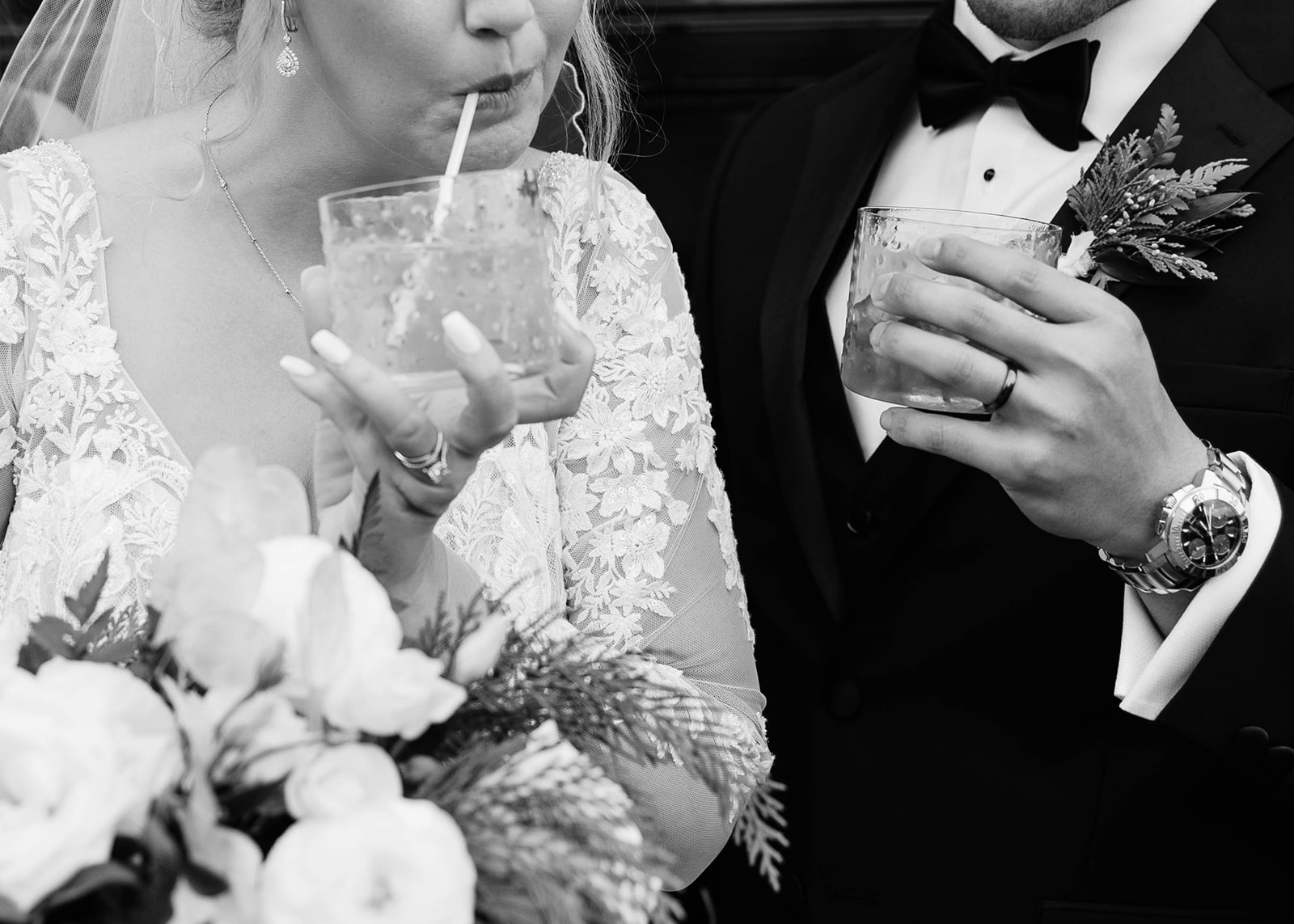 Close-up of the bride and groom sipping drinks together in black and white.