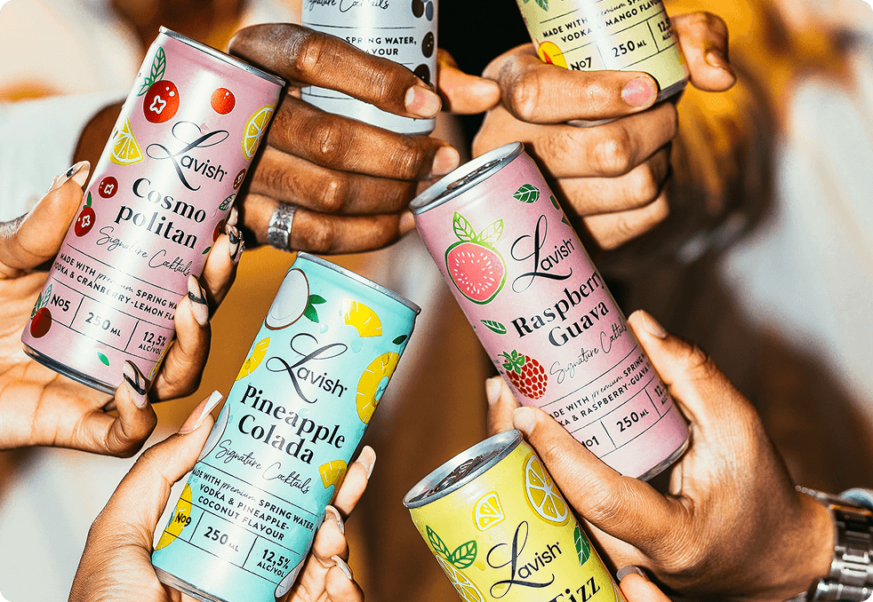 Four vibrant street-style tacos standing upright in hard shells, generously topped with shredded carrots, crispy fried protein, cilantro, and a creamy white sauce, served on a blue plate against a bright teal background.