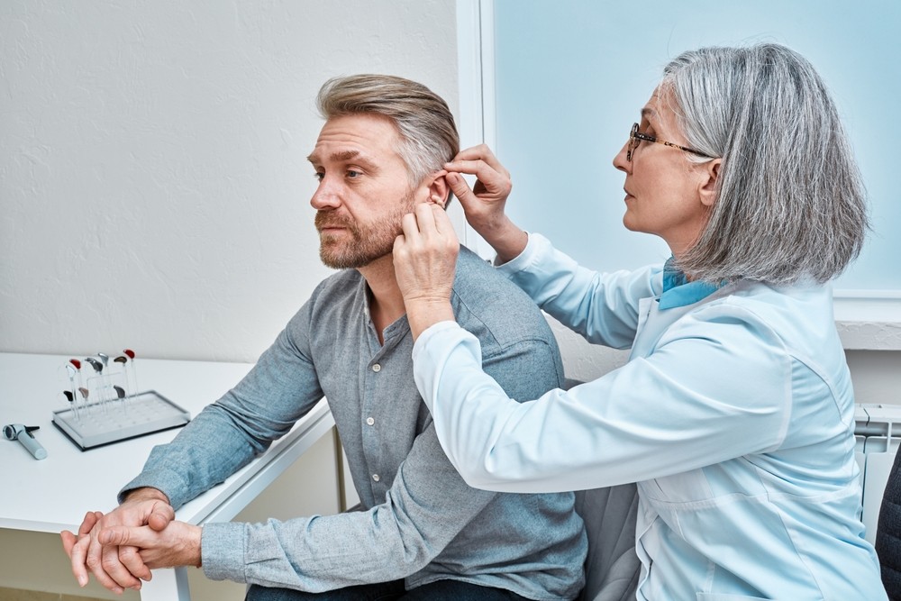 A person receiving an ear examination from a healthcare professional in a clinical setting.