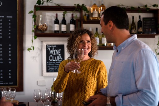 Couple enjoy a glamorous wine tasting. Lady looks at her partner's eyes with a very big smile