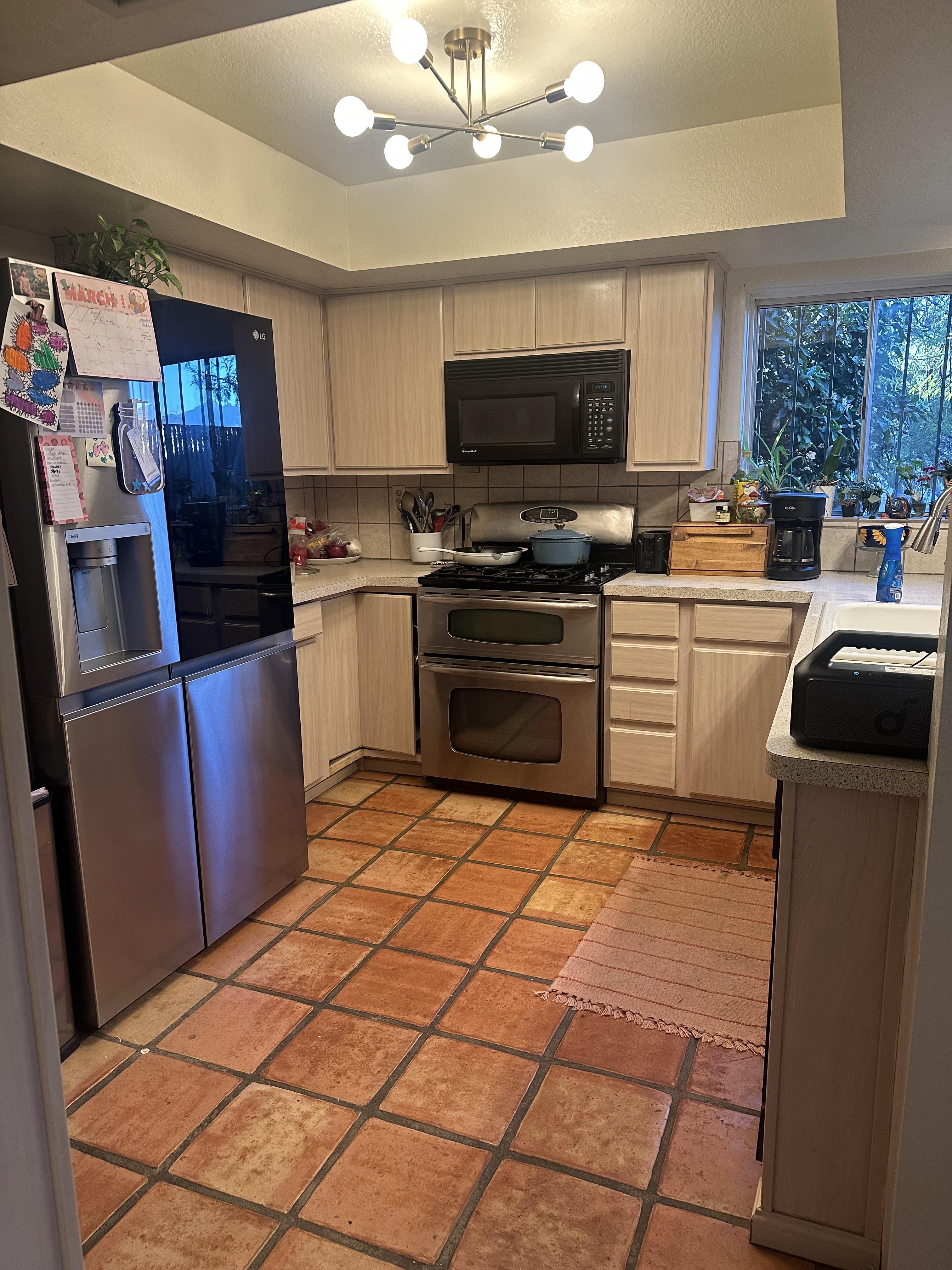 The original kitchen — faded pink cabinets, Saltillo terracotta tile, sputnik chandelier