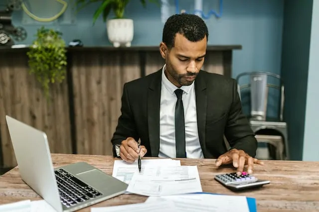 accountant looking at balance sheets and using a calculator