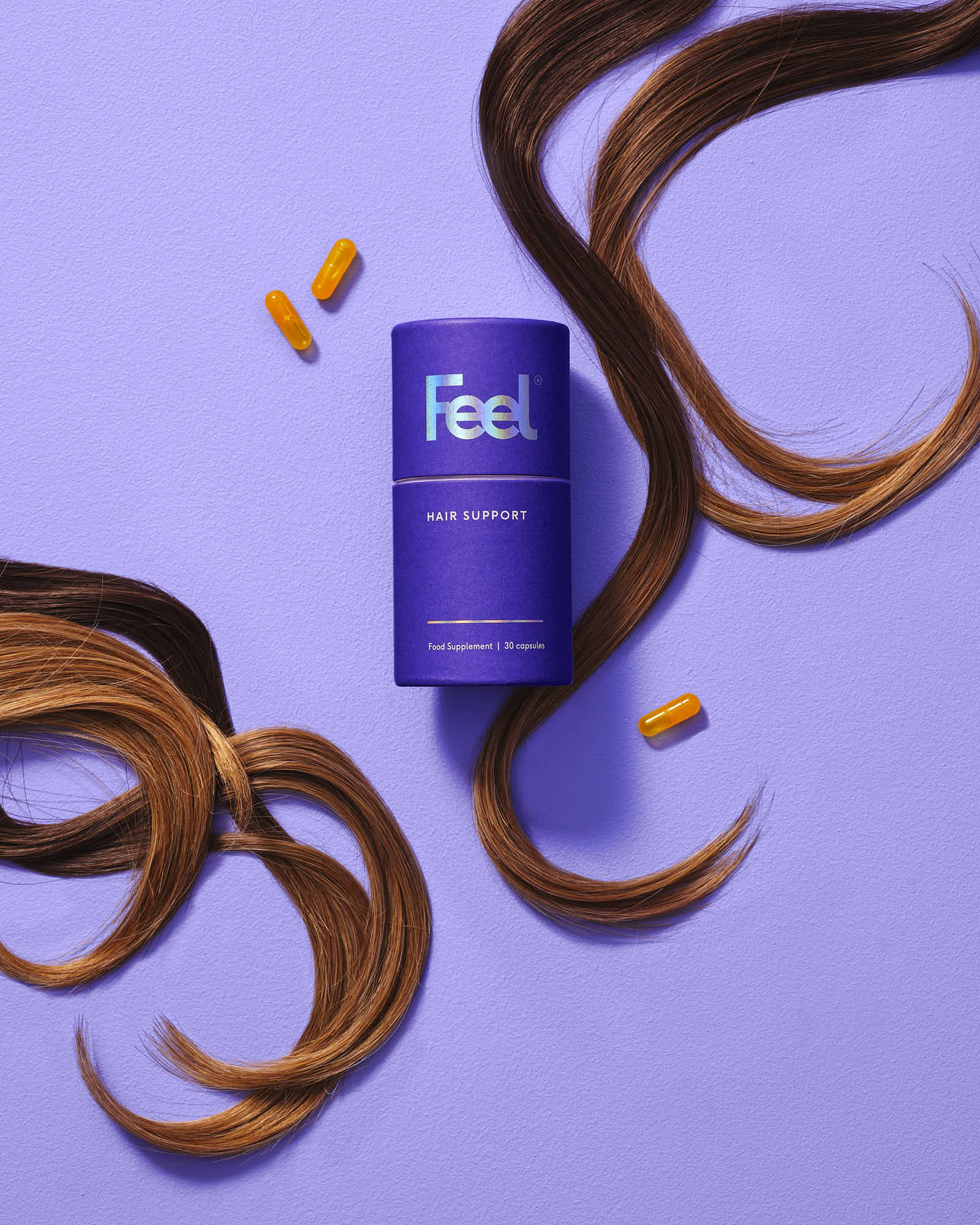 A purple hair product surrounded by flowing brown hair strands against a light purple background.