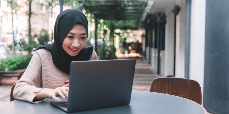 Seorang wanita Malaysia bekerja di laptop
