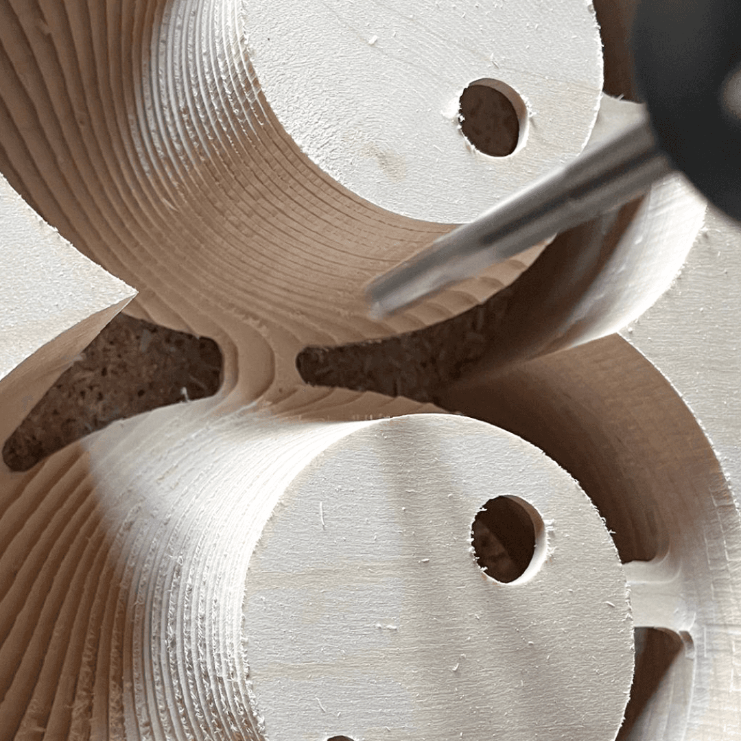 CNC milling machine carving wood into shade of over the ear headphones.