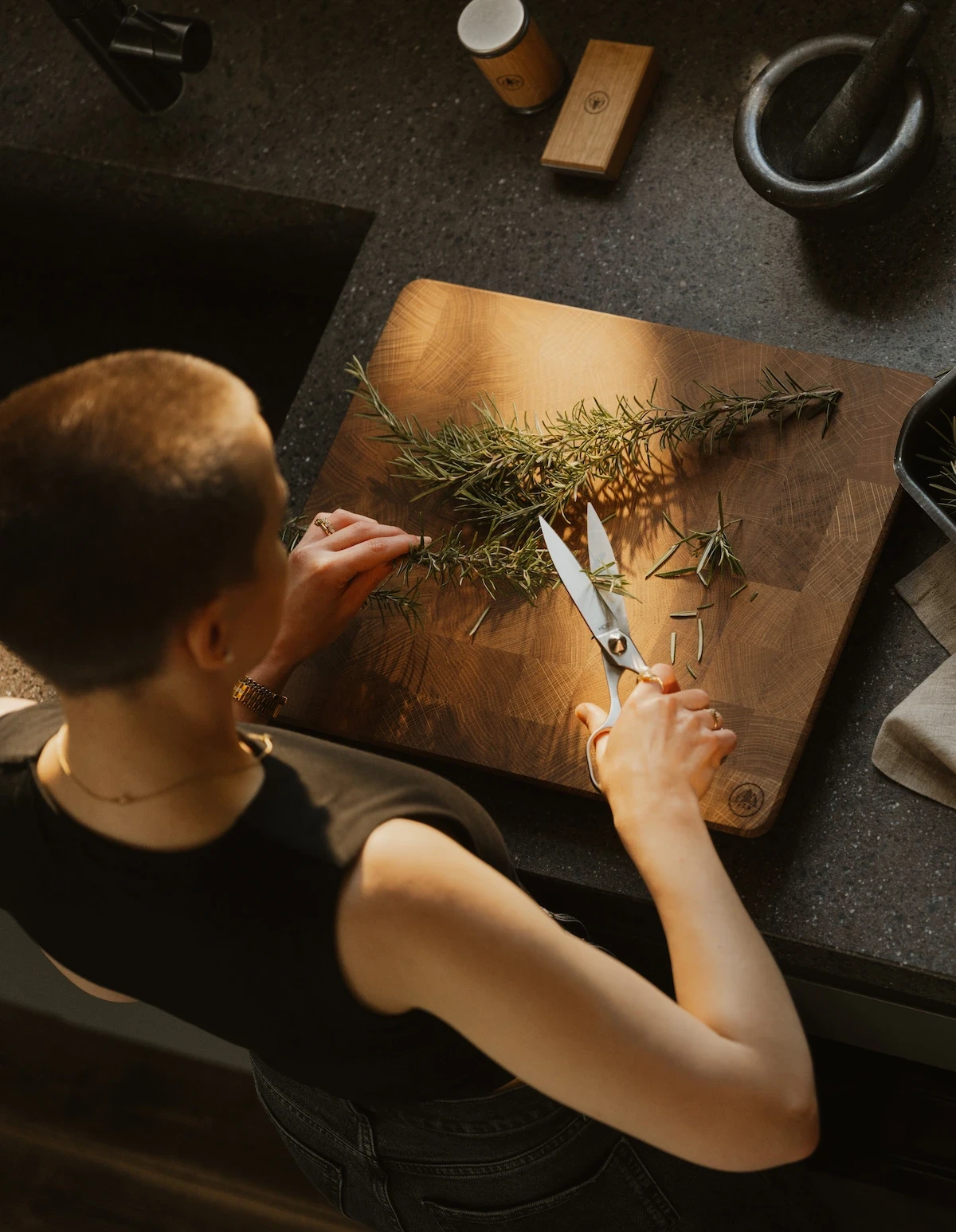 Close-up of a person using Horl stainless steel household scissors to cut fresh green herbs in a kitchen setting.