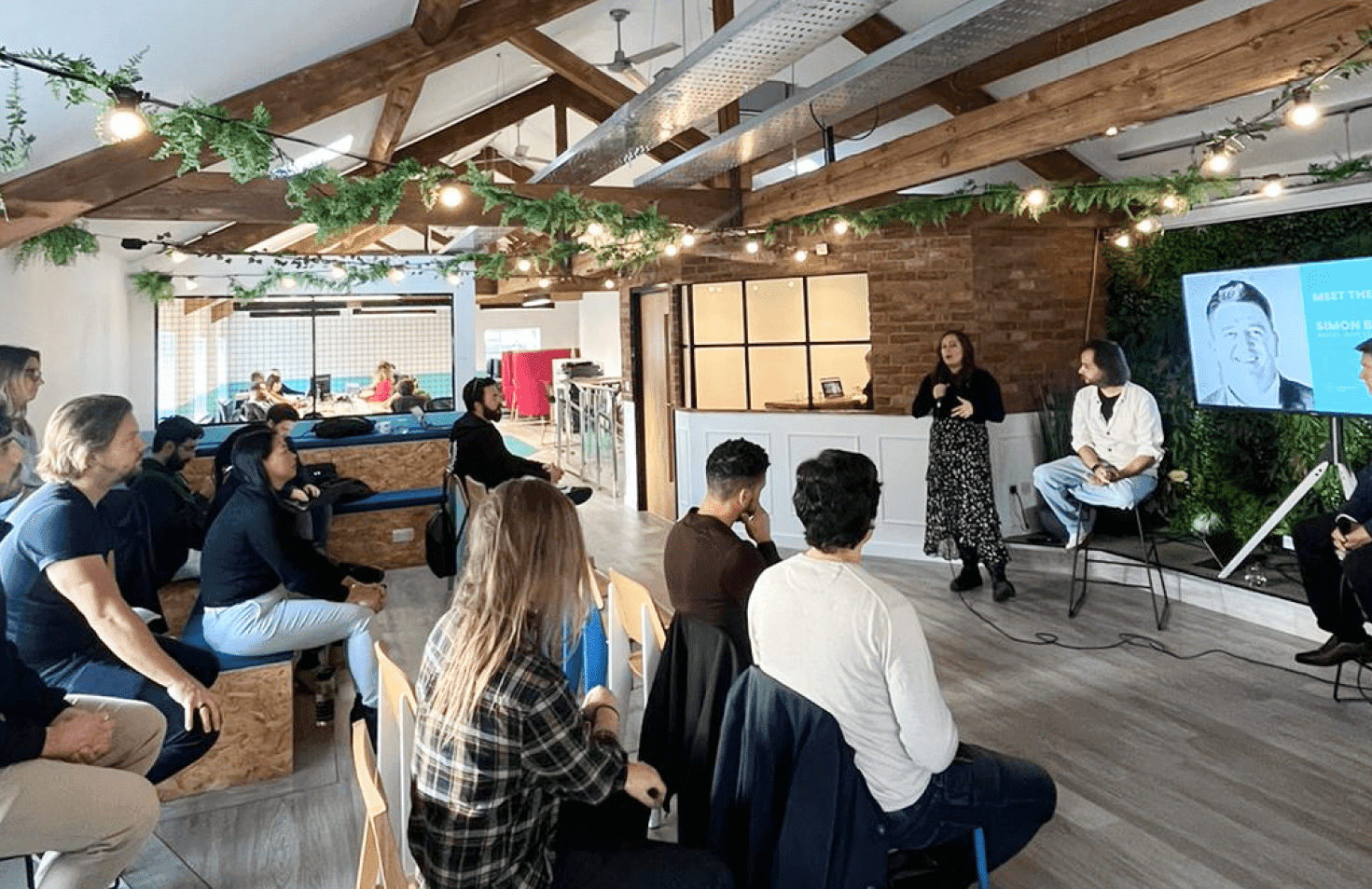 People sitting and watching a screen inside an indoor structure.