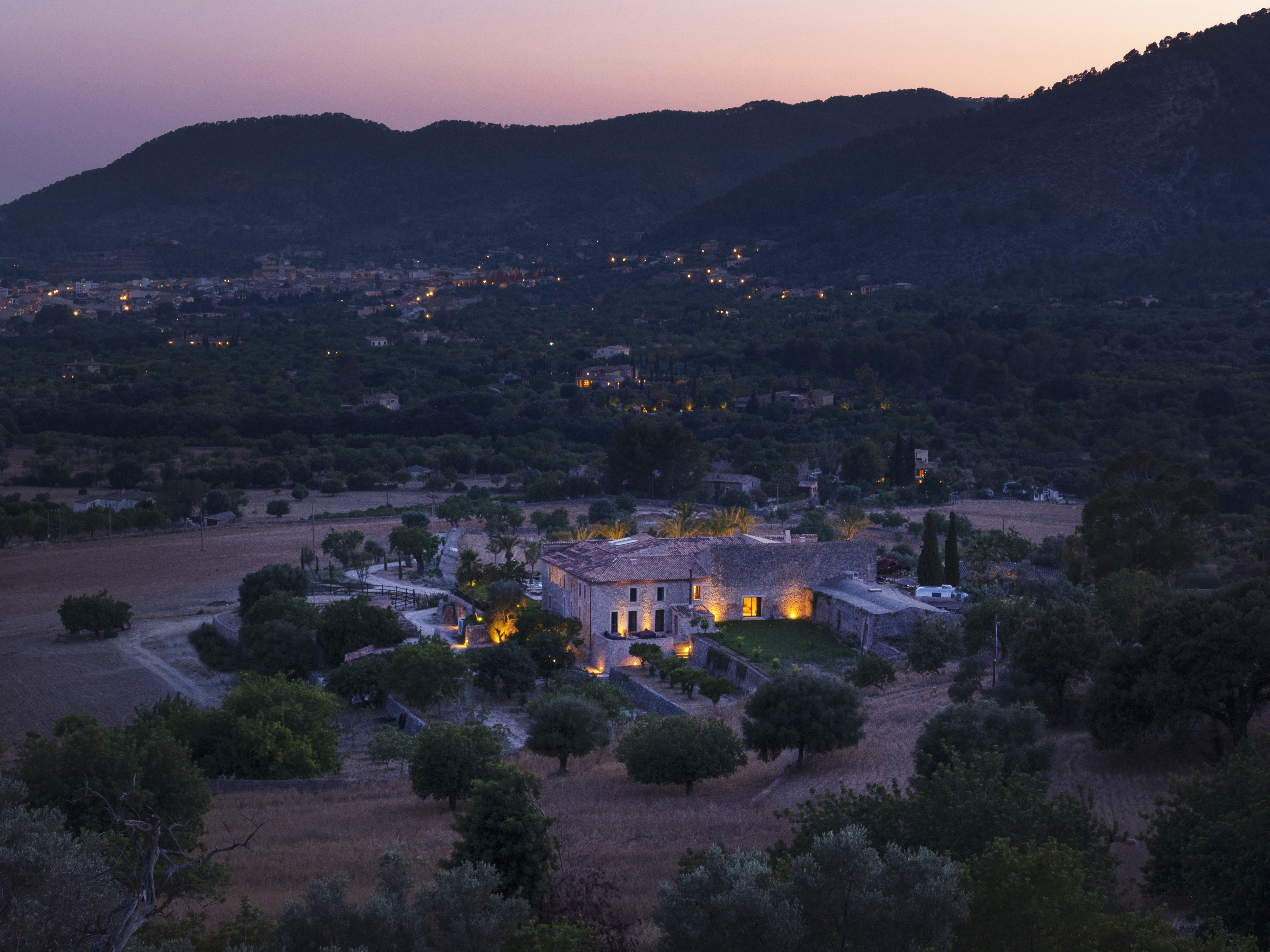 Image of a hotel in the distance with mountains at sunset