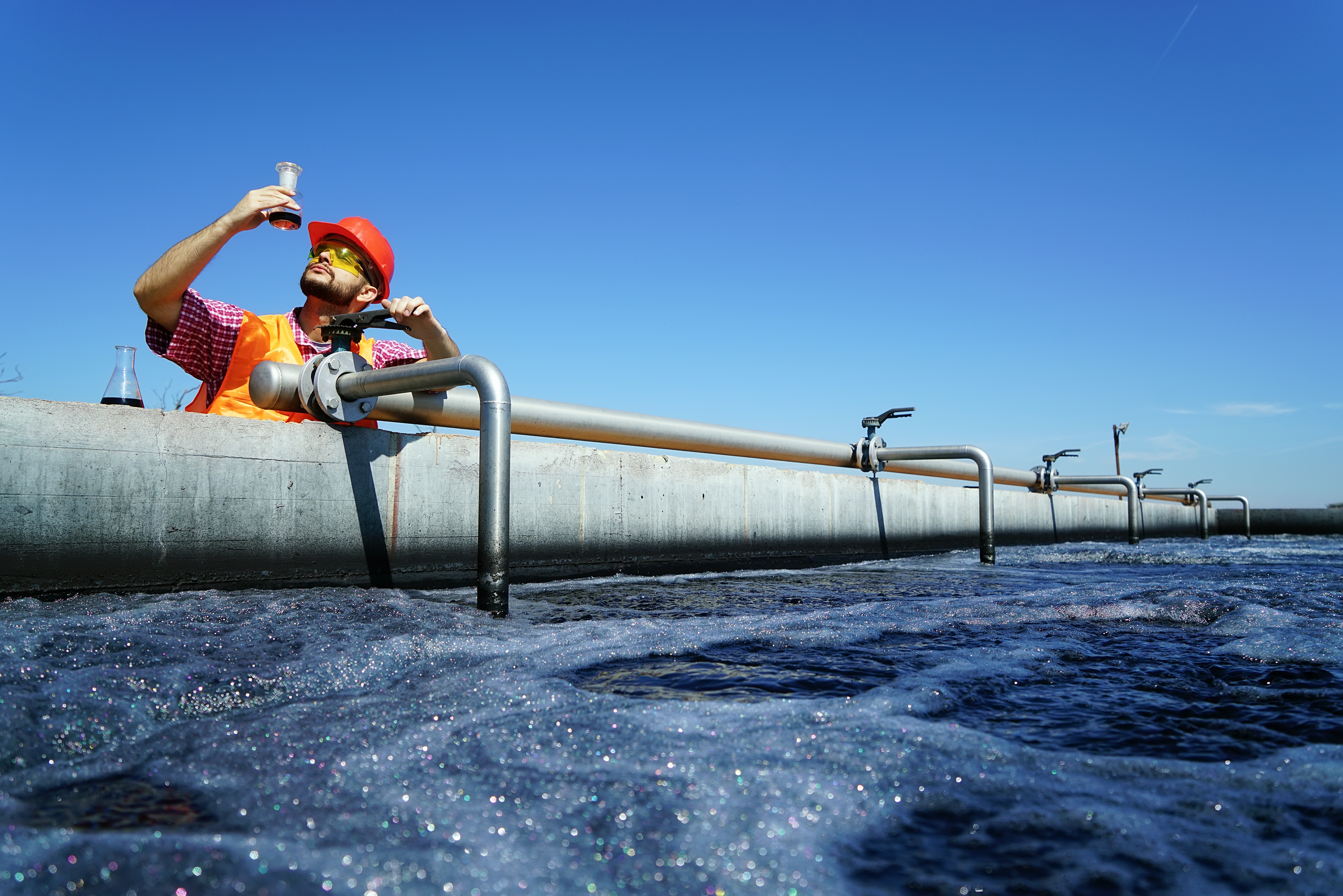 An expert checking water in a beaker next to an external water source. 