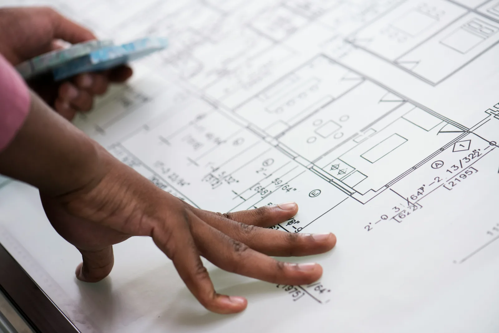 Ръка разглежда подробен план на етаж на маса