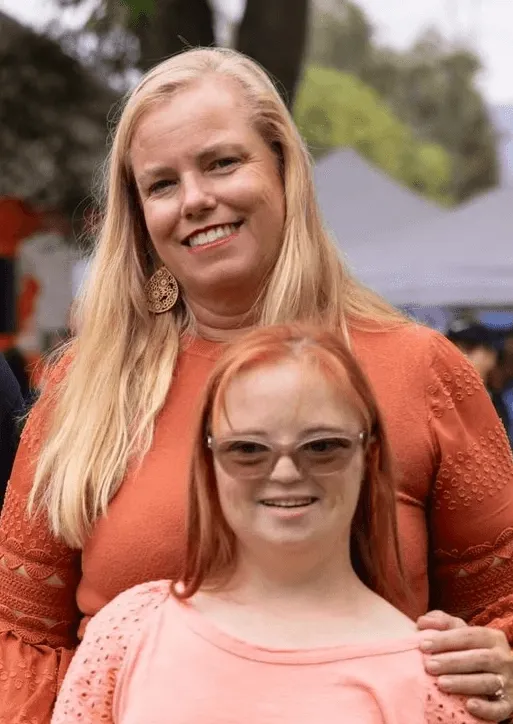 A woman and a girl posing together at an outdoor event.