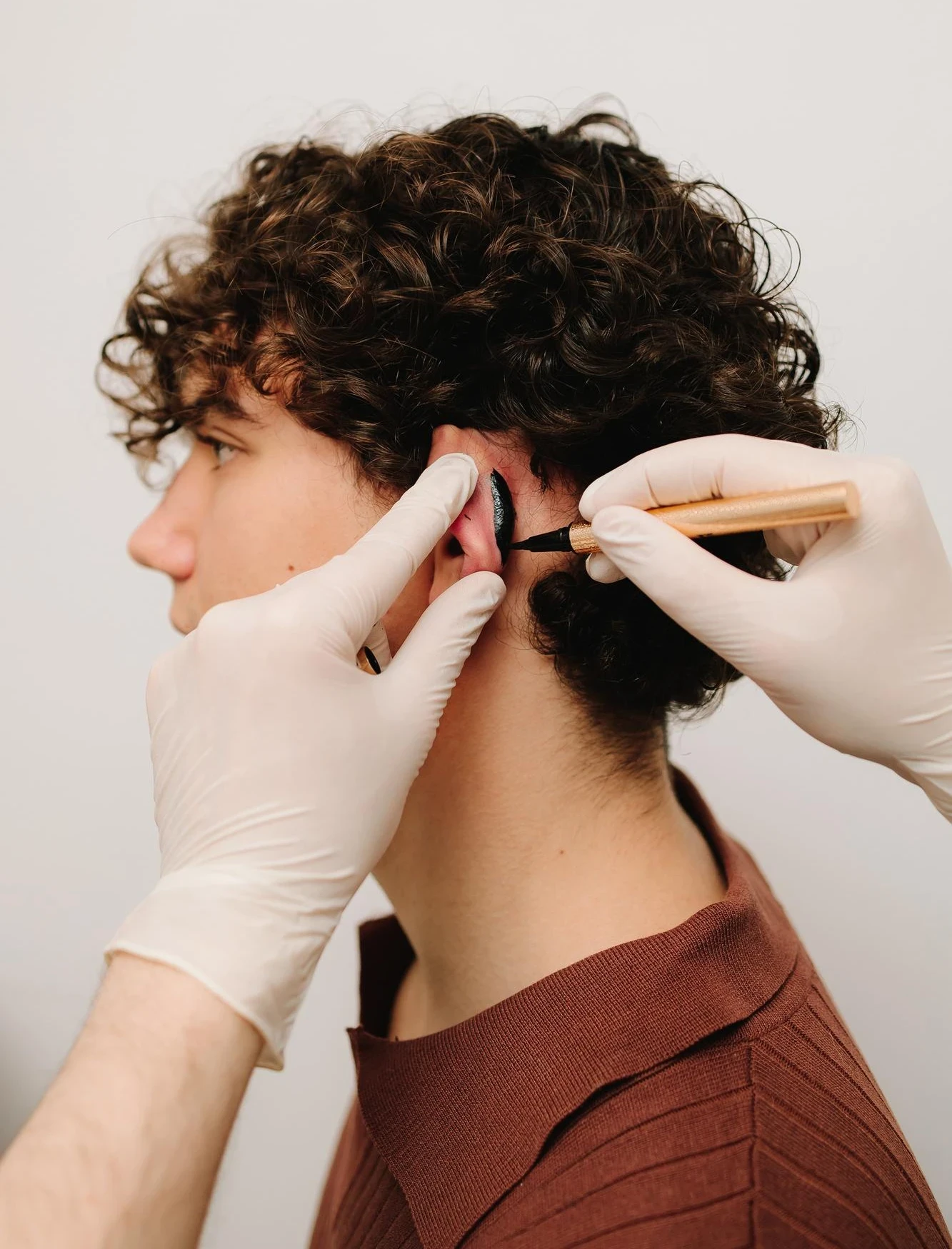 Jeune homme se faisant percer une oreille.