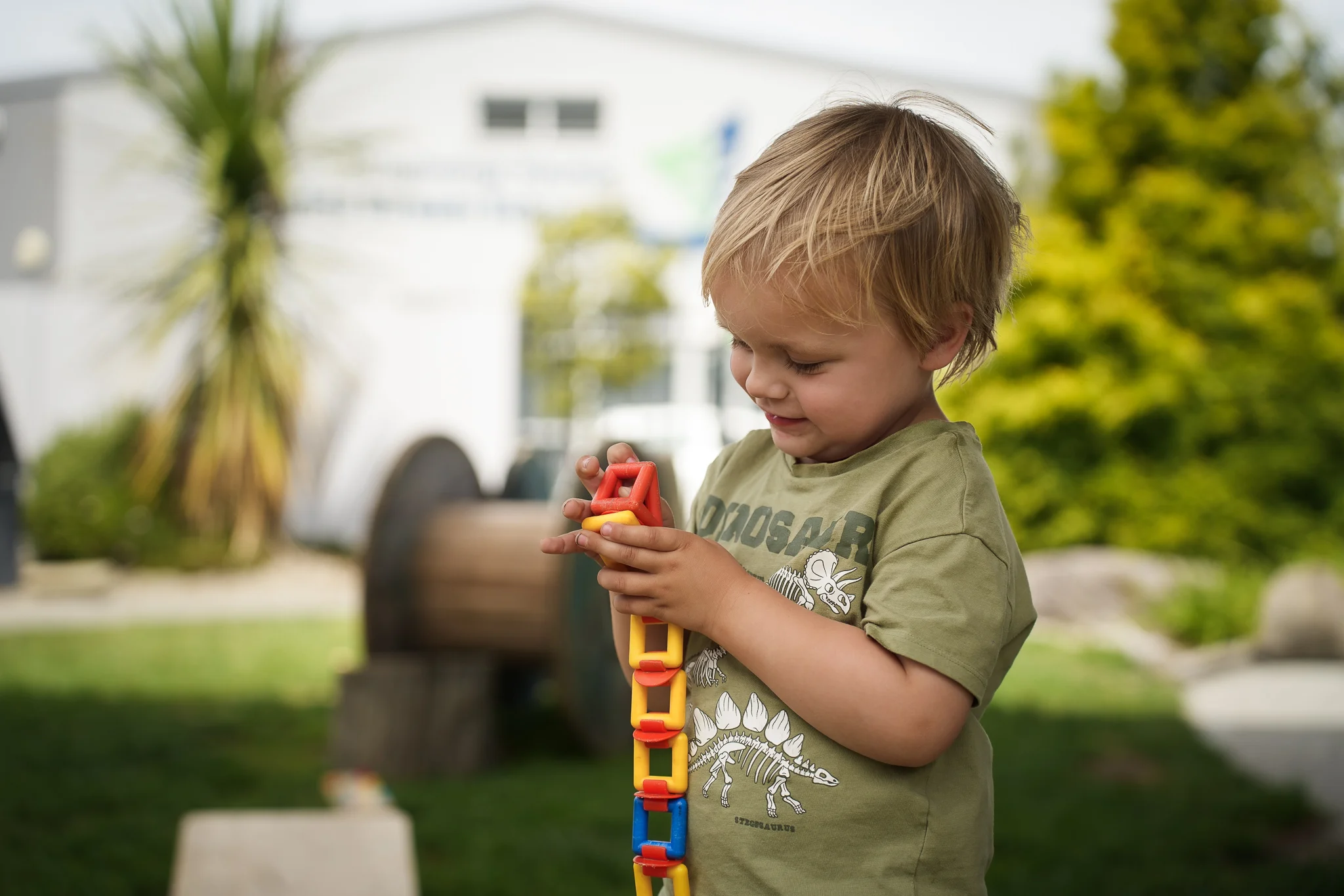 A young boy outside playing with a red ball