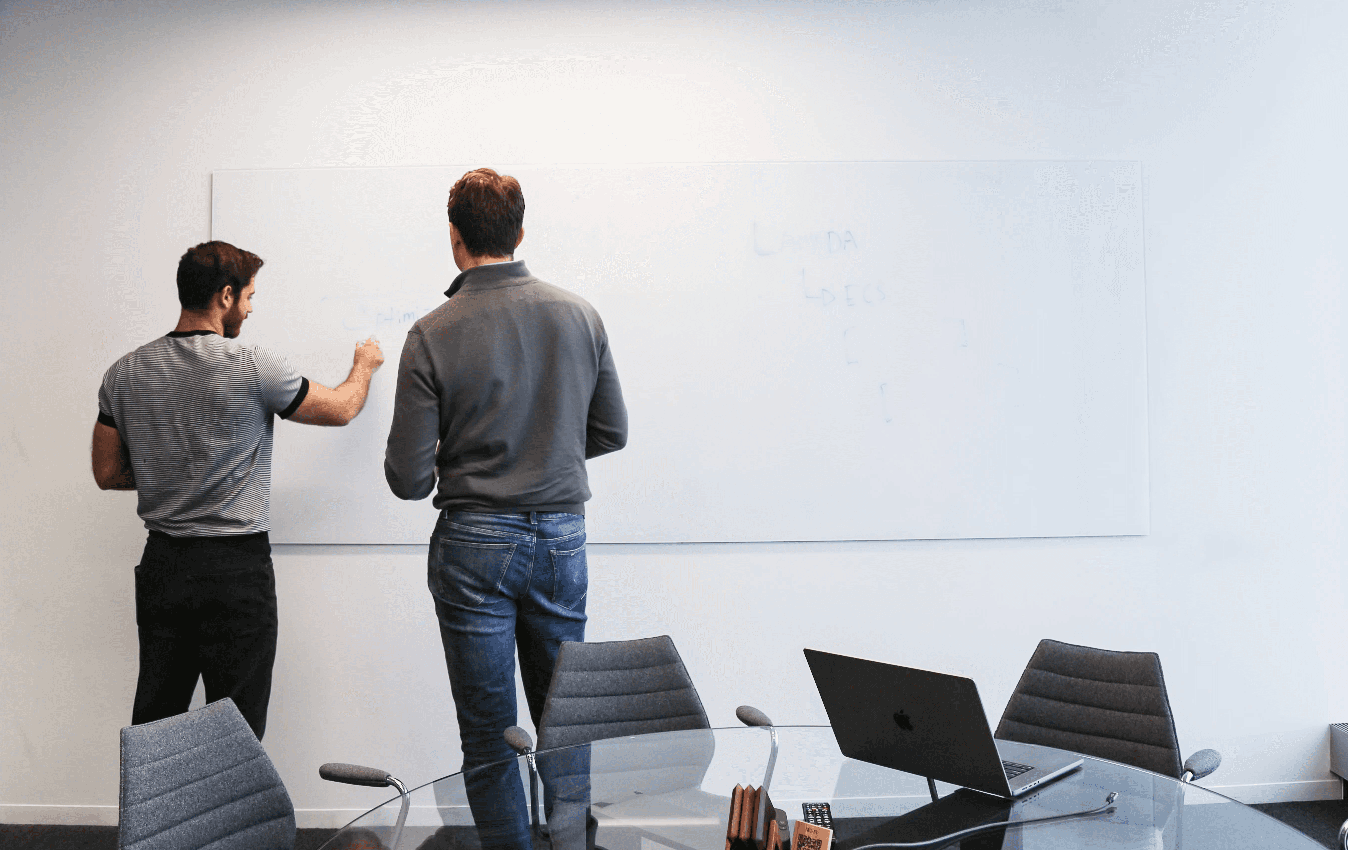 Two employees standing at a white board talking