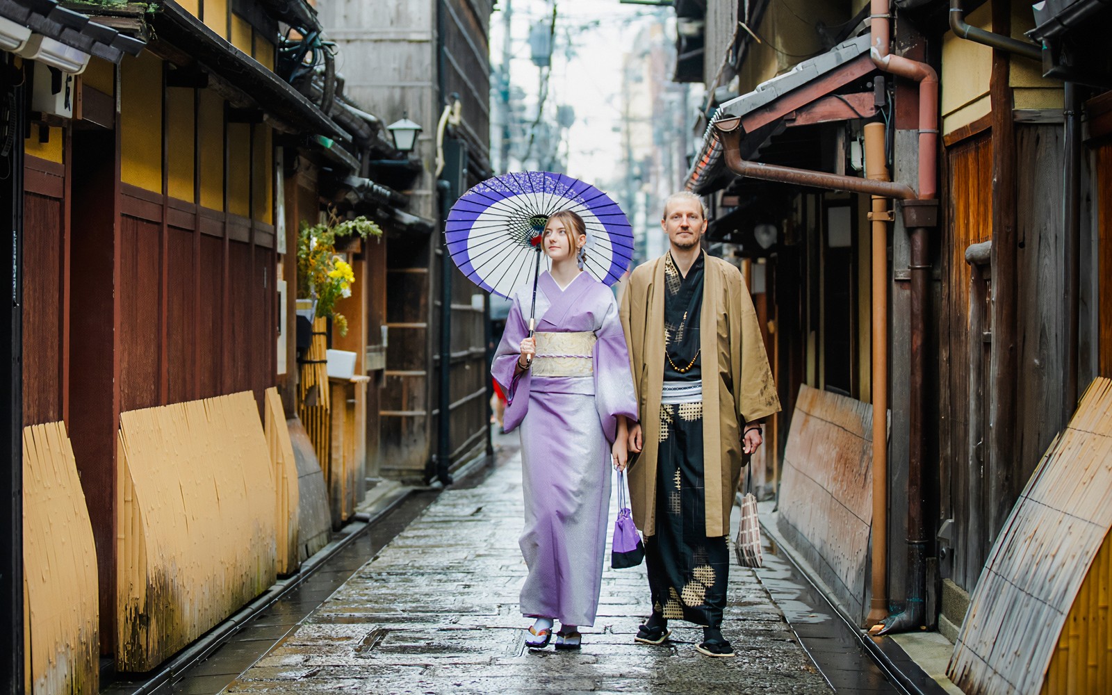 Pareja en kimono tradicional caminando por una calle histórica de Kioto.
