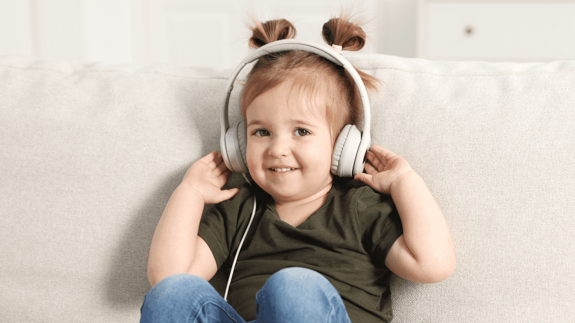 A young girl sitting on a sofa, wearing headphones and enjoying HushAway®’s Sound Sanctuary.