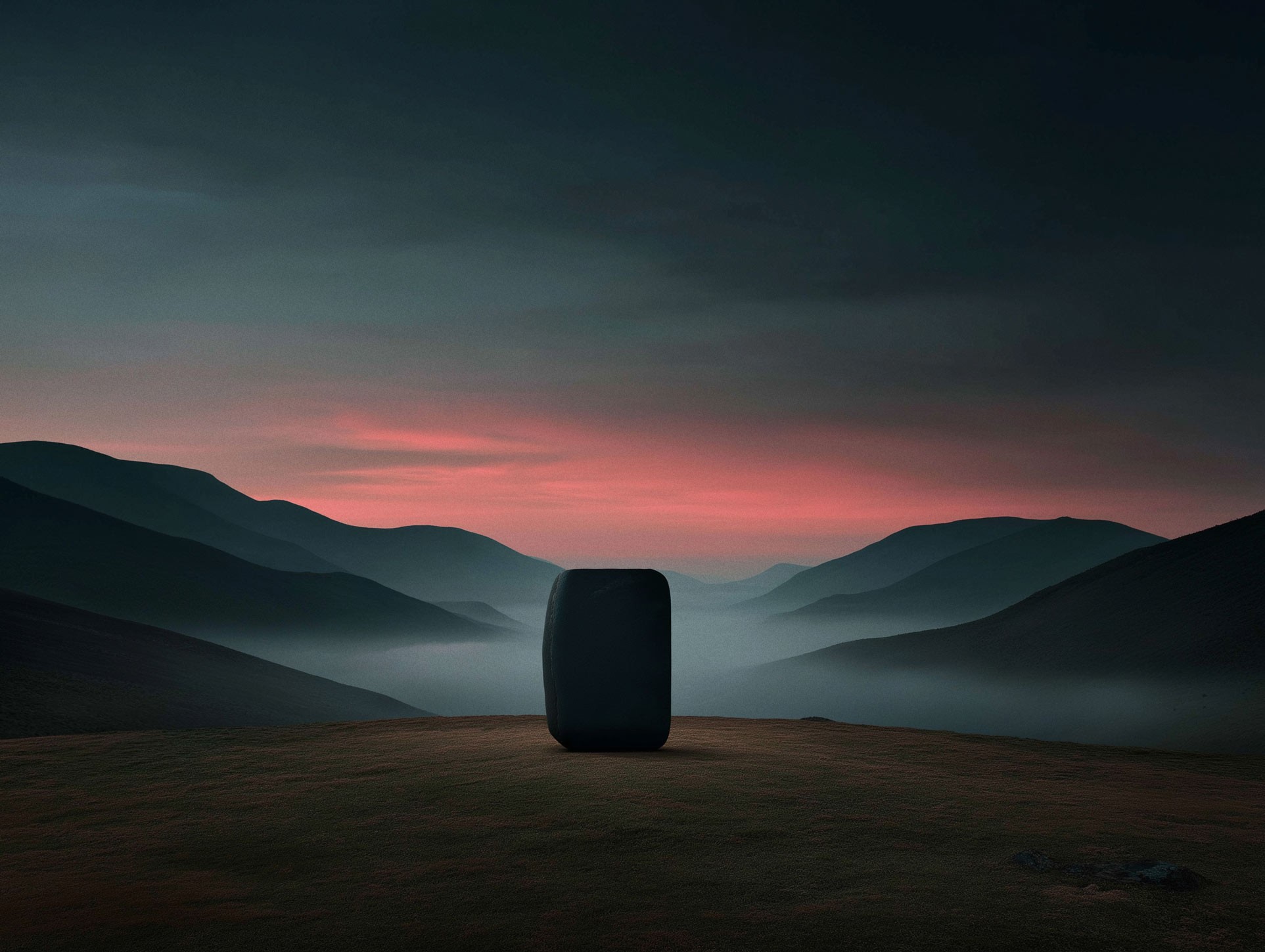 Misty mountain range with warm sunset glow on the horizon