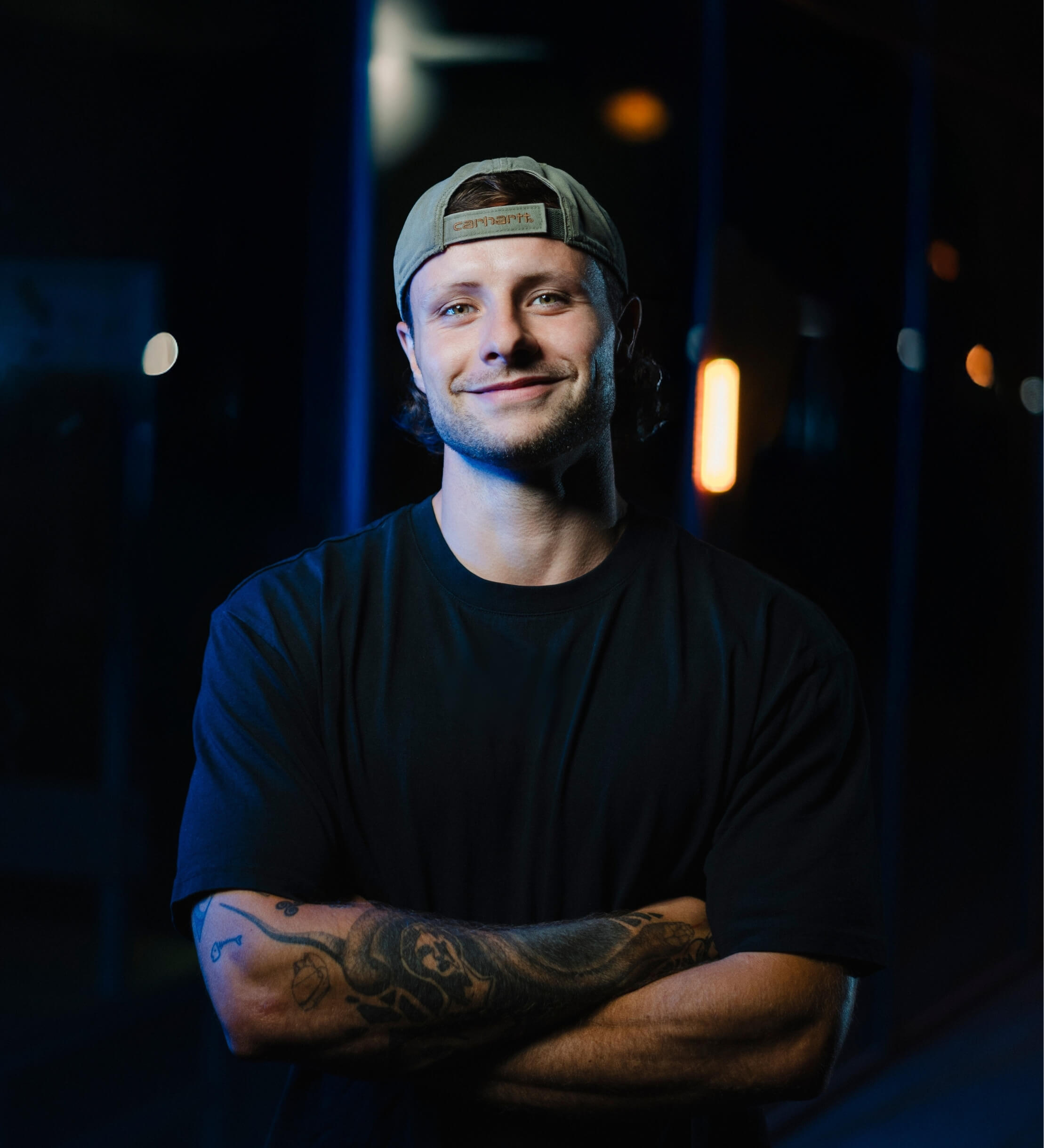 Smiling young man in a black t-shirt against a gray background, radiating warmth and friendliness.